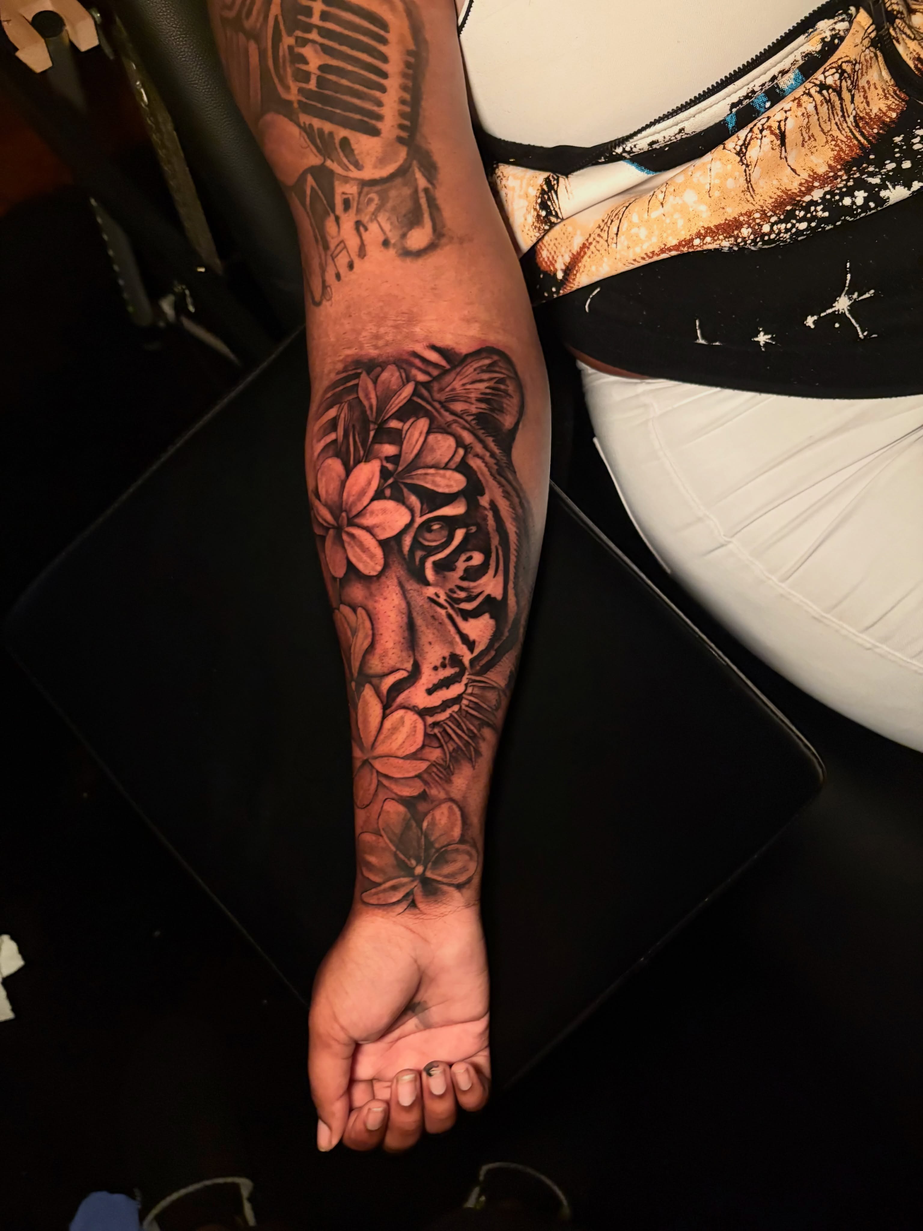 Tiger with flowers realism tattoo on the forearm by Maleek Inkz