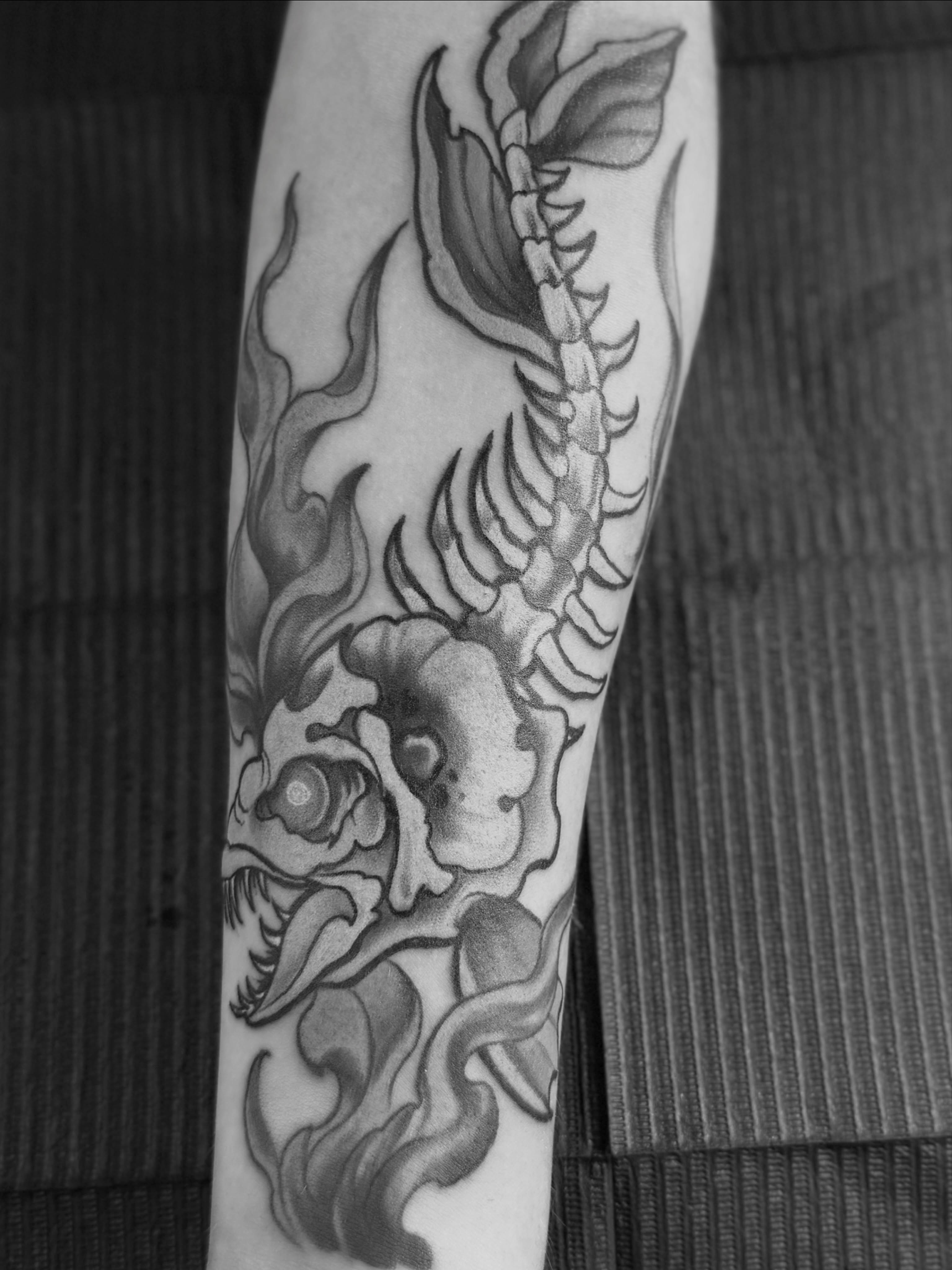 Skull and spine black and grey tattoo on the forearm by Blue Horseshoe Tattoo & Body Piercing