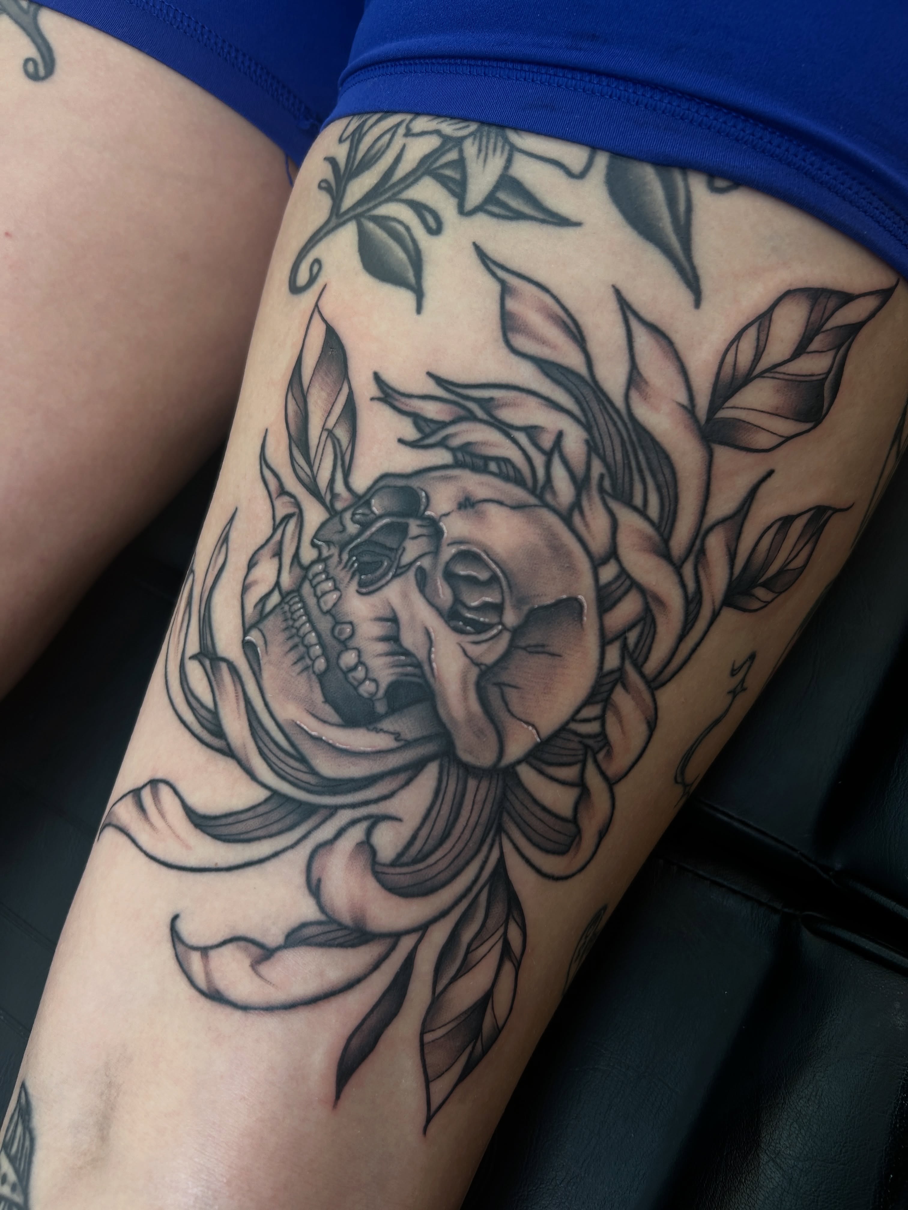 Skull and floral realism tattoo on the thigh by Dylan James
