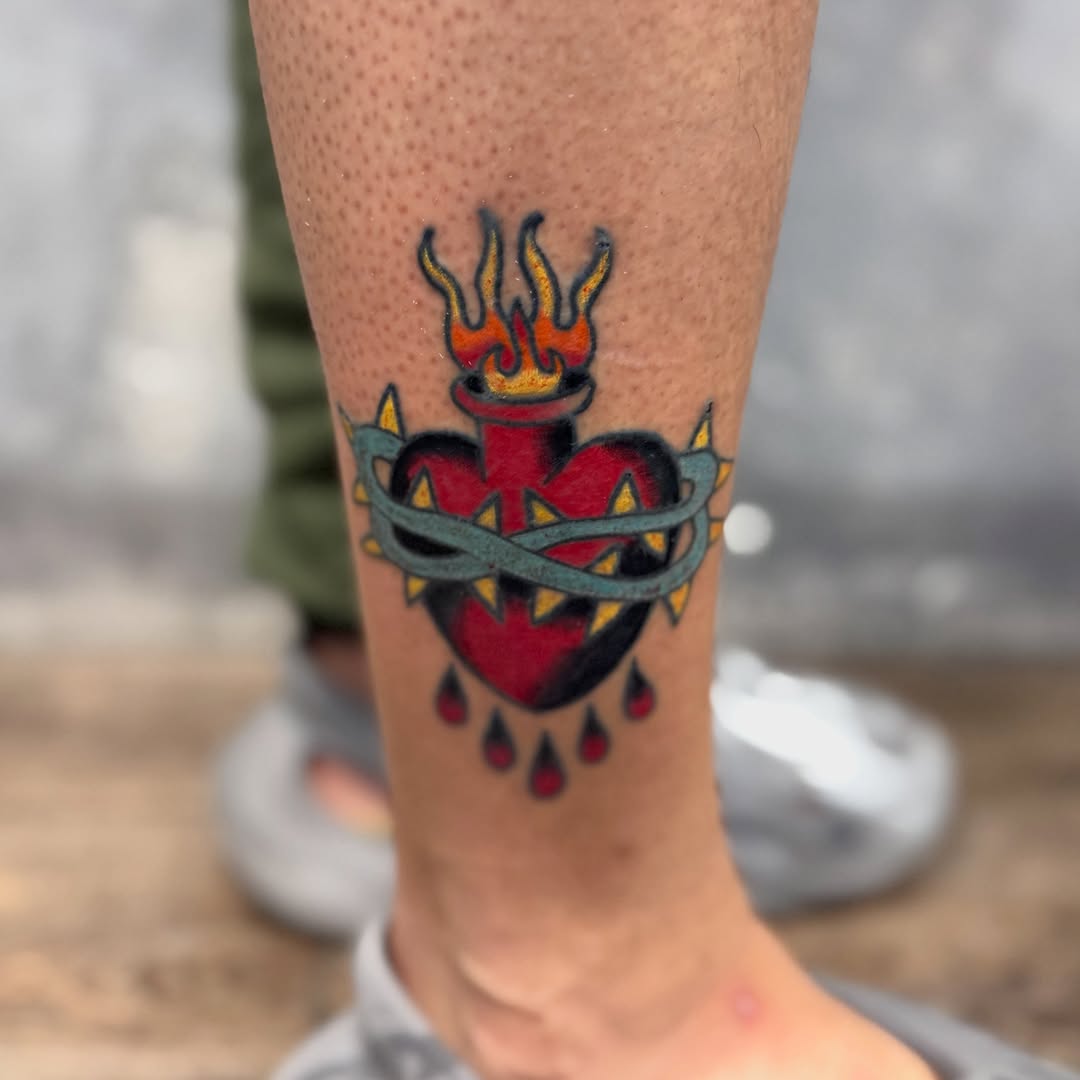 Flame-topped heart American traditional tattoo on the forearm by Camilo