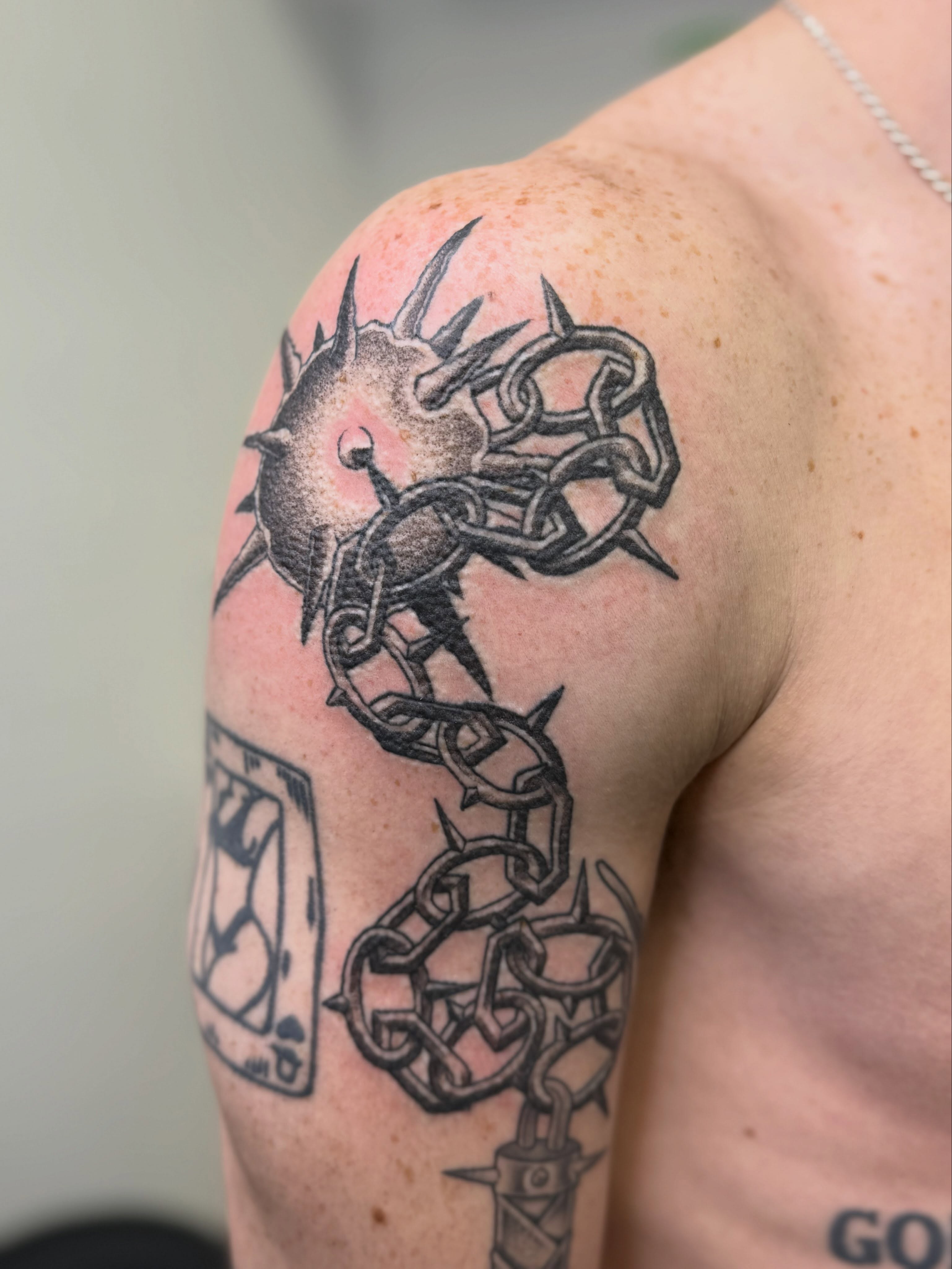 Chain and spike black and grey tattoo on the shoulder by Austin Poliszuk, Minneapolis, Minnesota