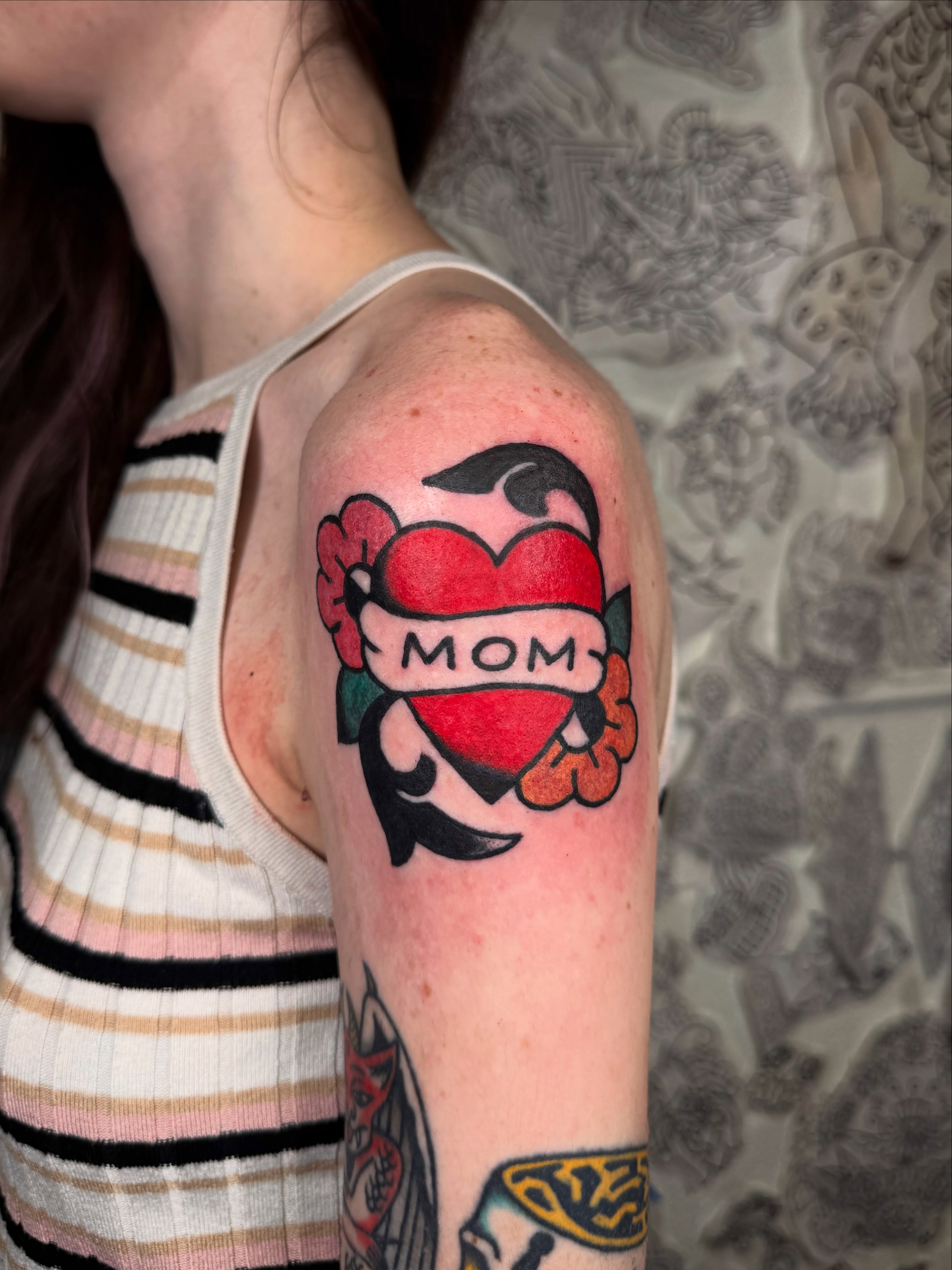 Heart with 'mom' banner American traditional tattoo on the forearm by lily gustave i tattoo