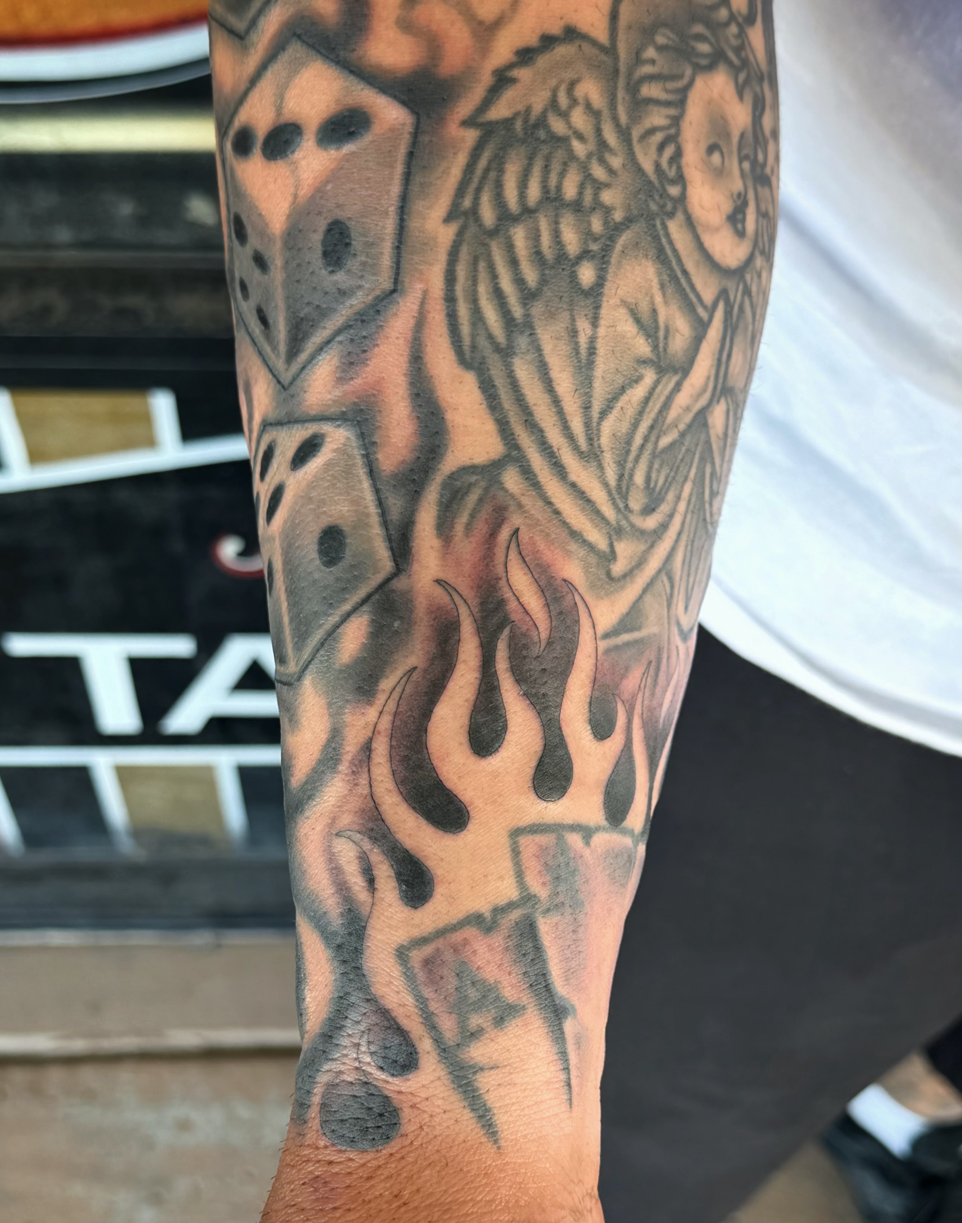 Angel with dice and flames American traditional tattoo on the forearm by @sloanxkettering