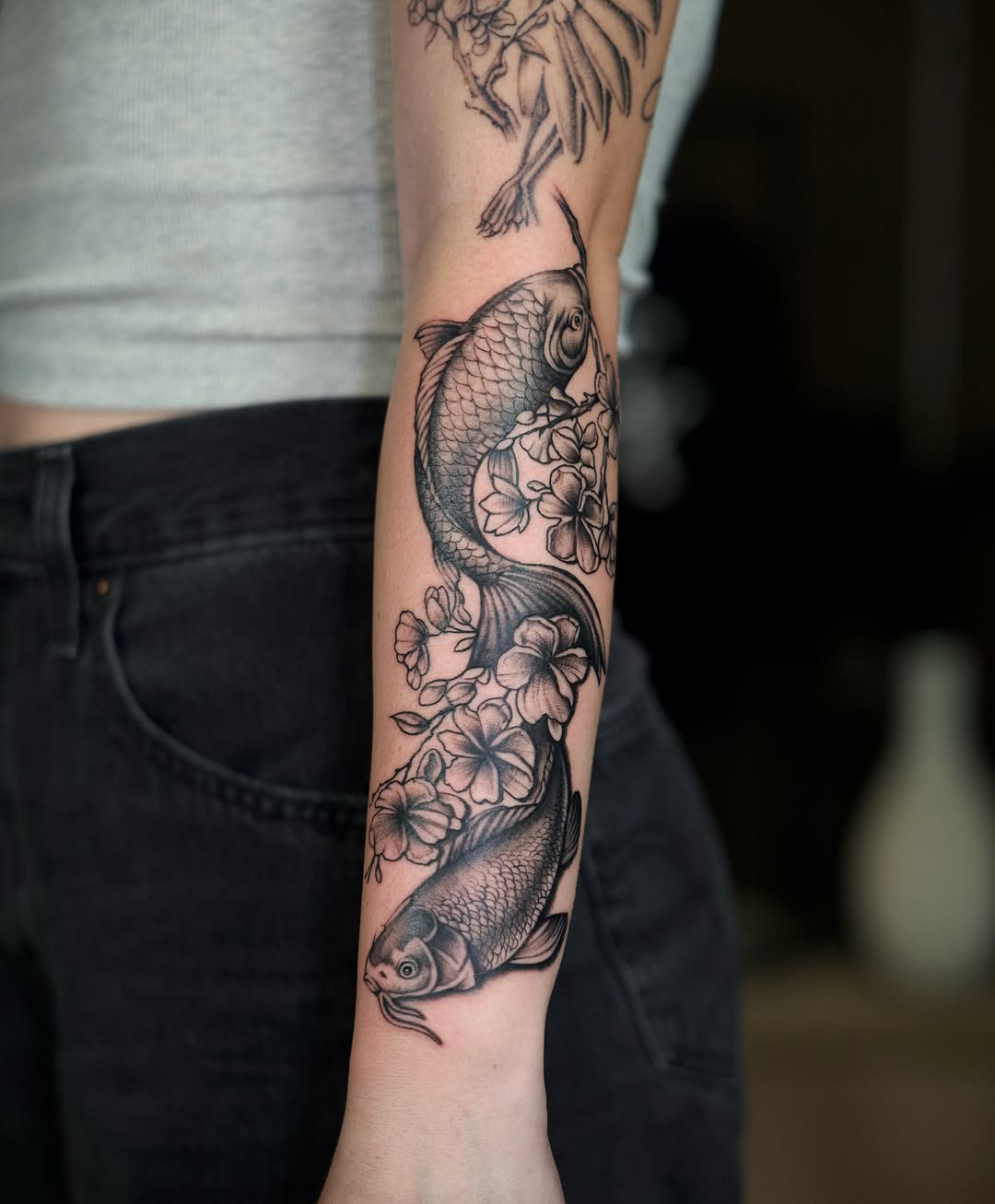 Koi fish and flowers realism tattoo on the forearm by @lovechasetattoo