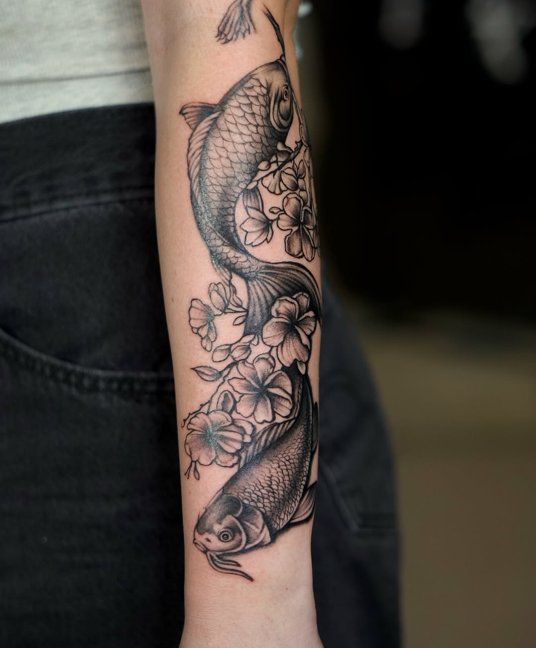 Koi fish and flowers realism tattoo on the forearm by @lovechasetattoo