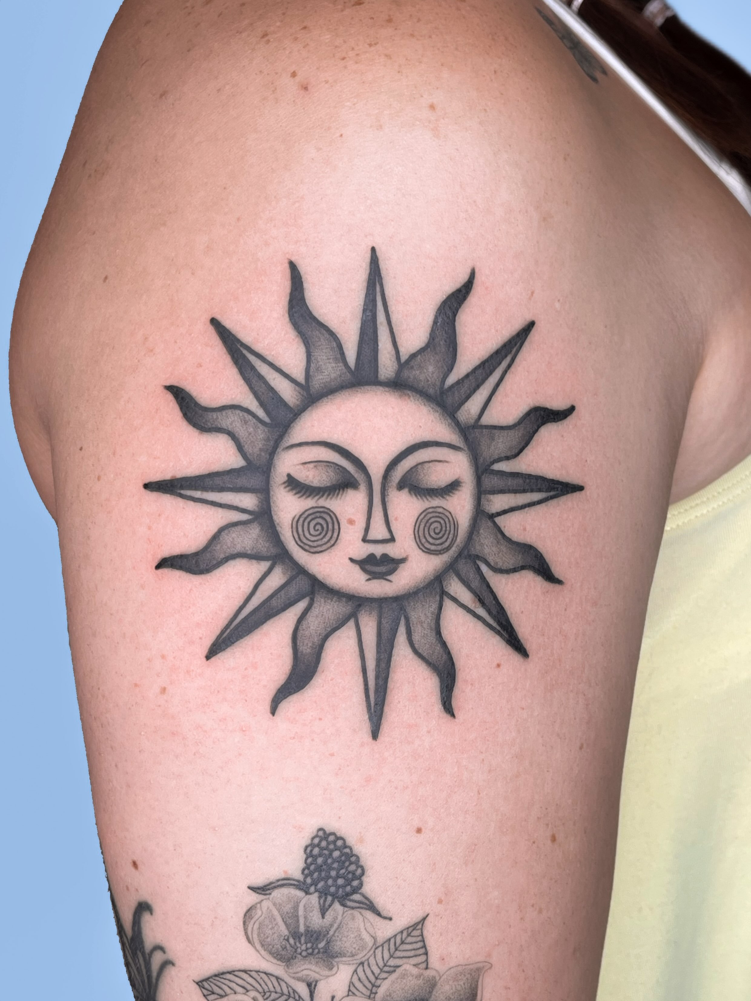 Sun with face black and grey tattoo on the shoulder by nina