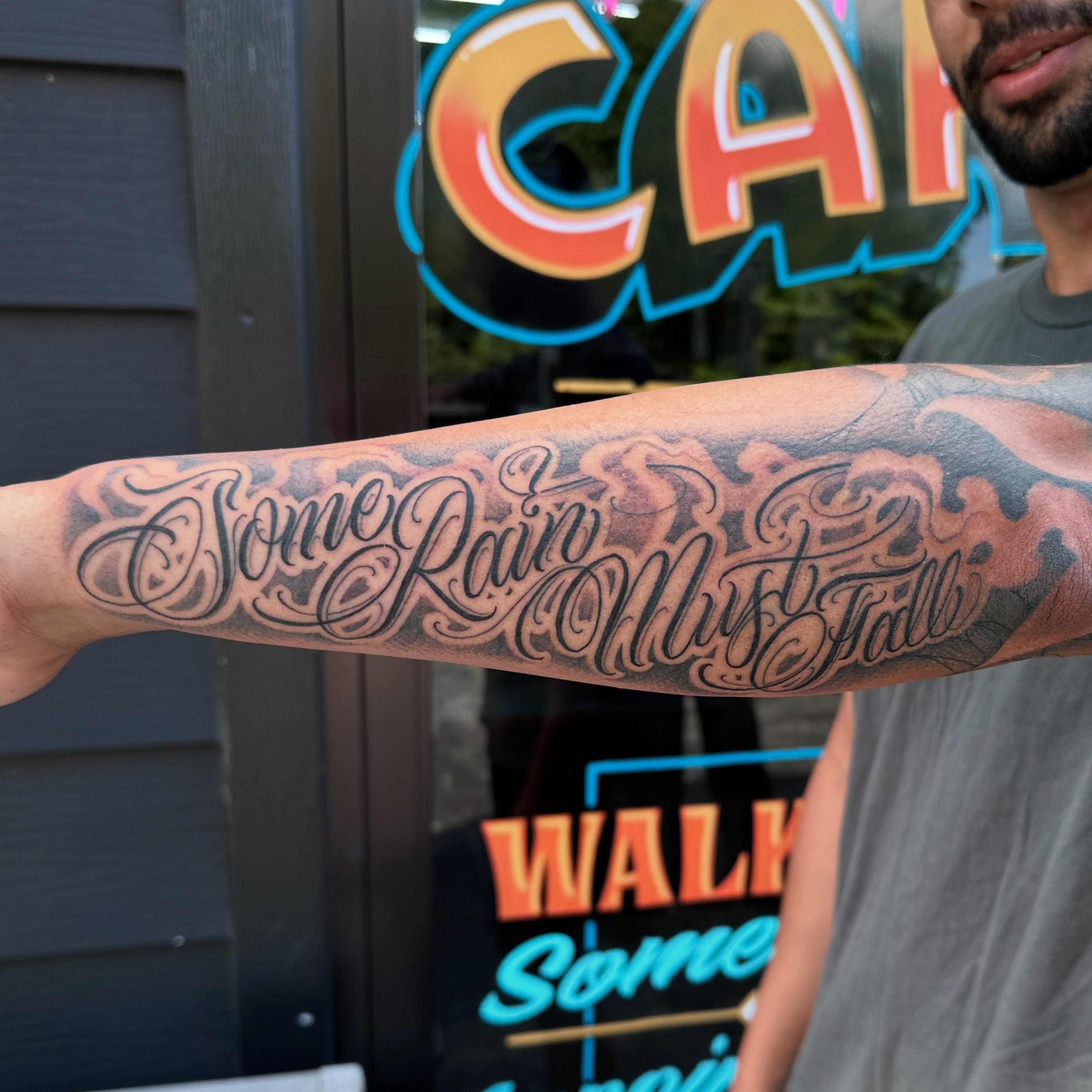 Some Rain Must Fall lettering script tattoo on the forearm by Dustin Clark, Dayton, Ohio