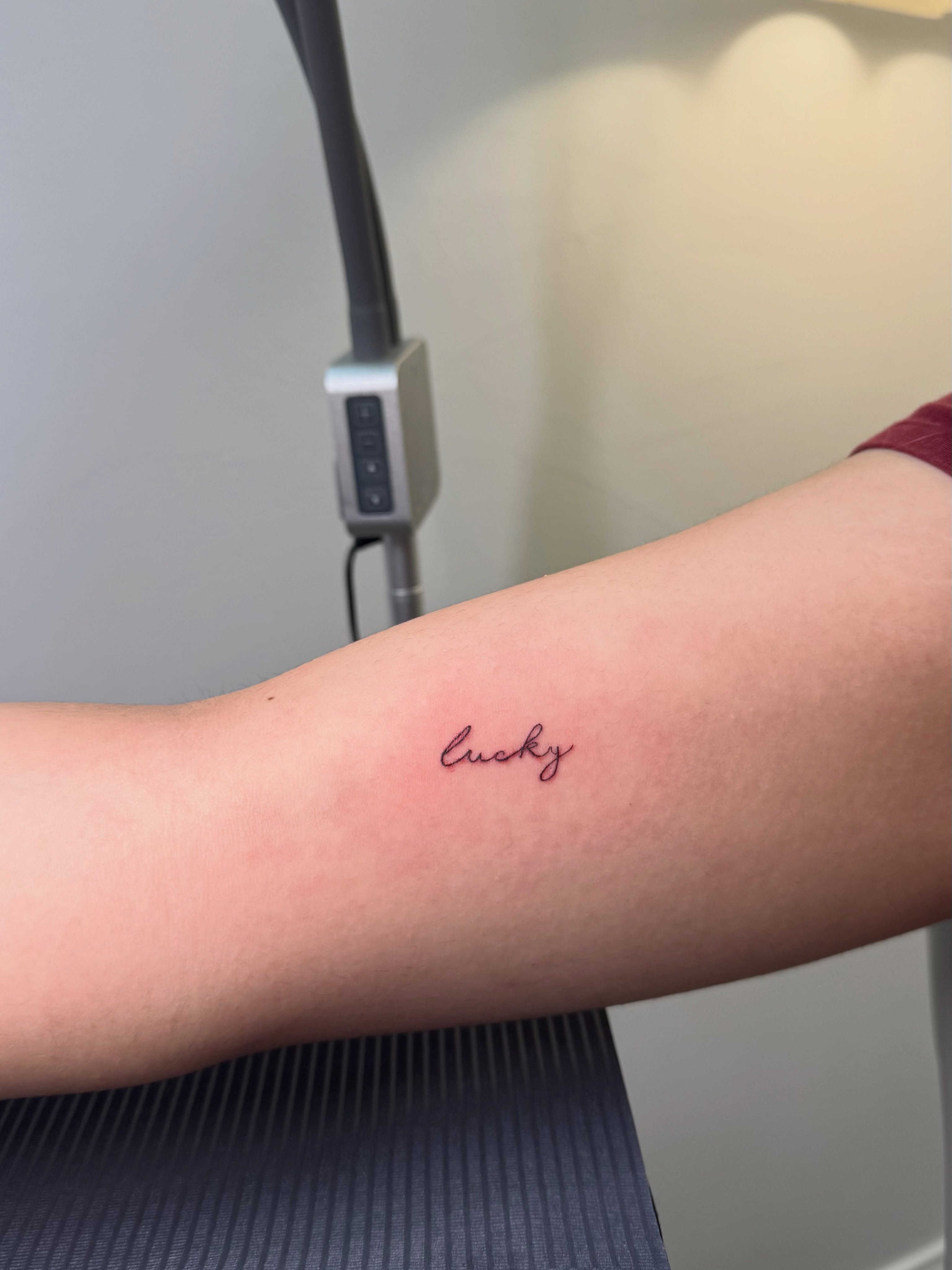 Lucky lettering script tattoo on the forearm by Nicole