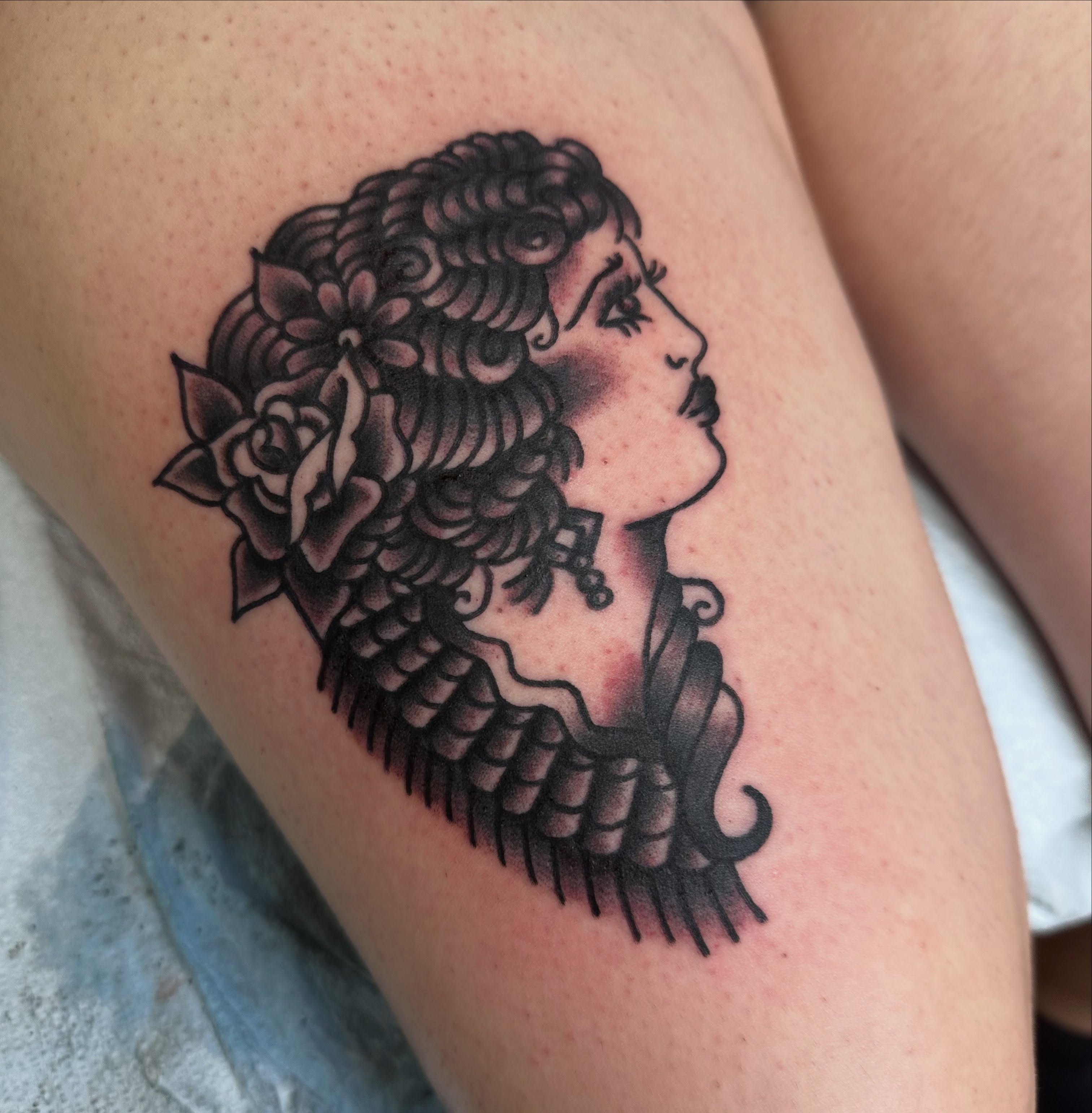 Profile of a woman American traditional tattoo on the thigh by norawillstattoo