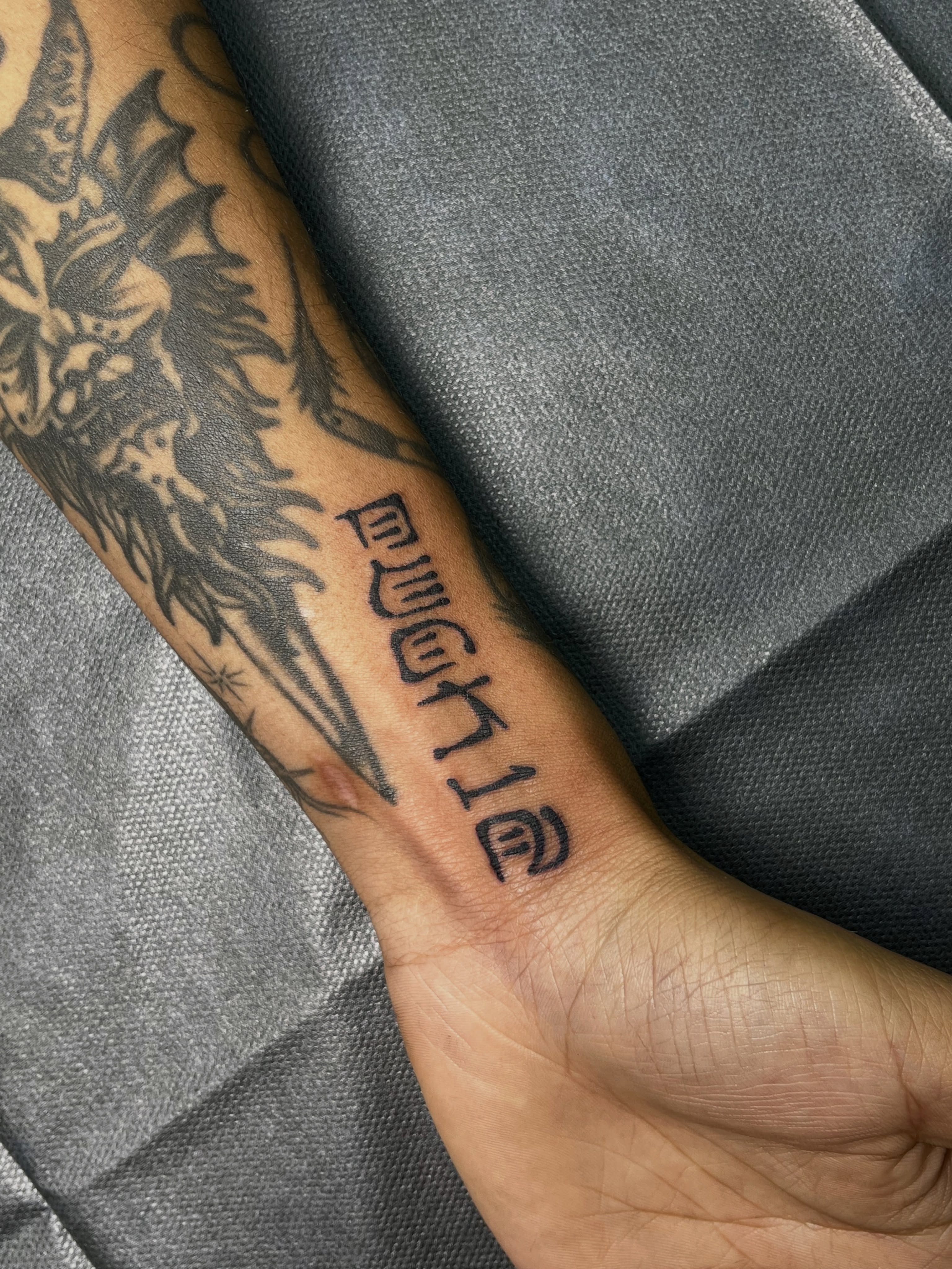 Hebrew script black and grey tattoo on the forearm by christina diaz