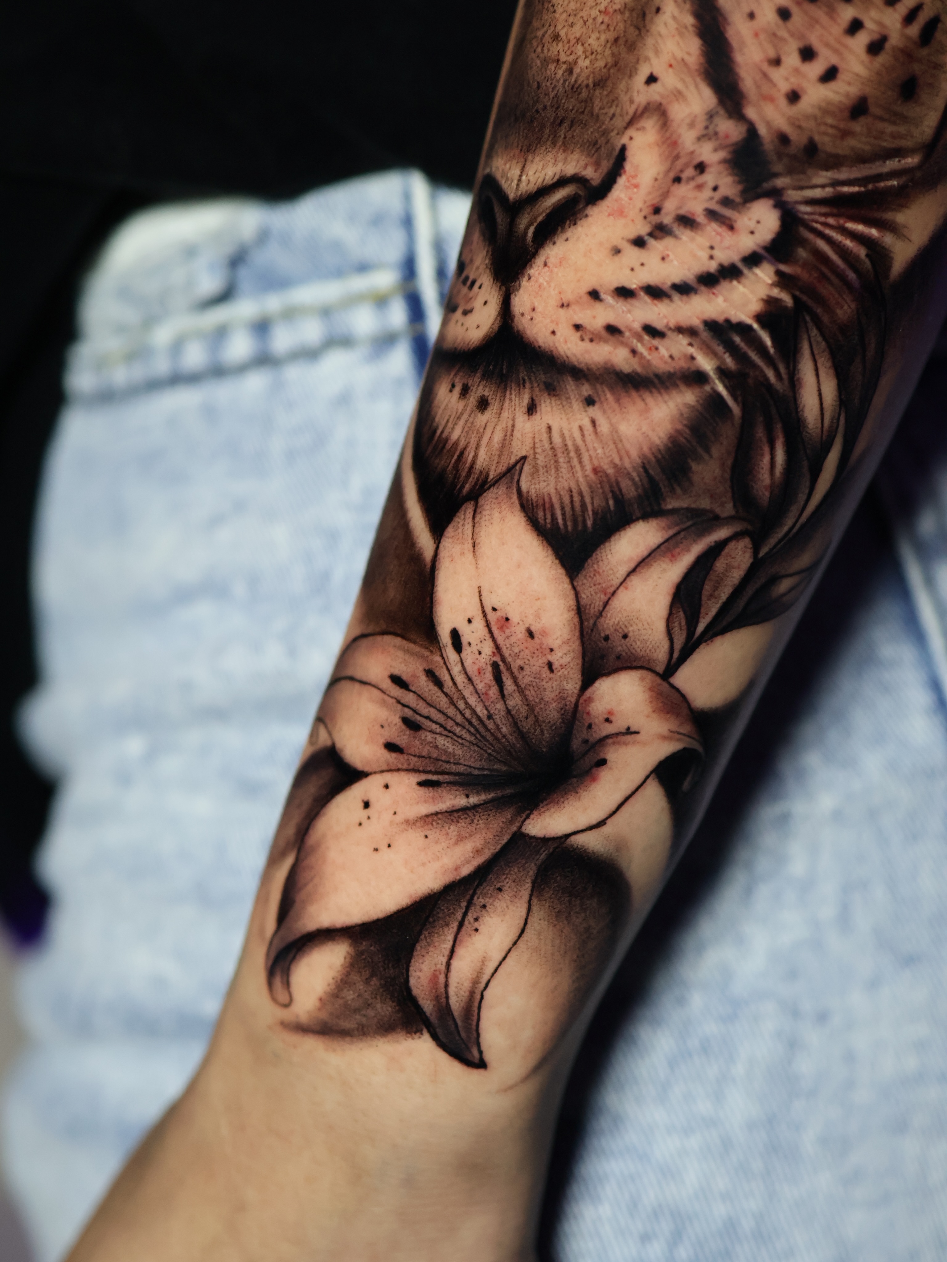 Lily black and grey tattoo on the forearm by German Patiño.
