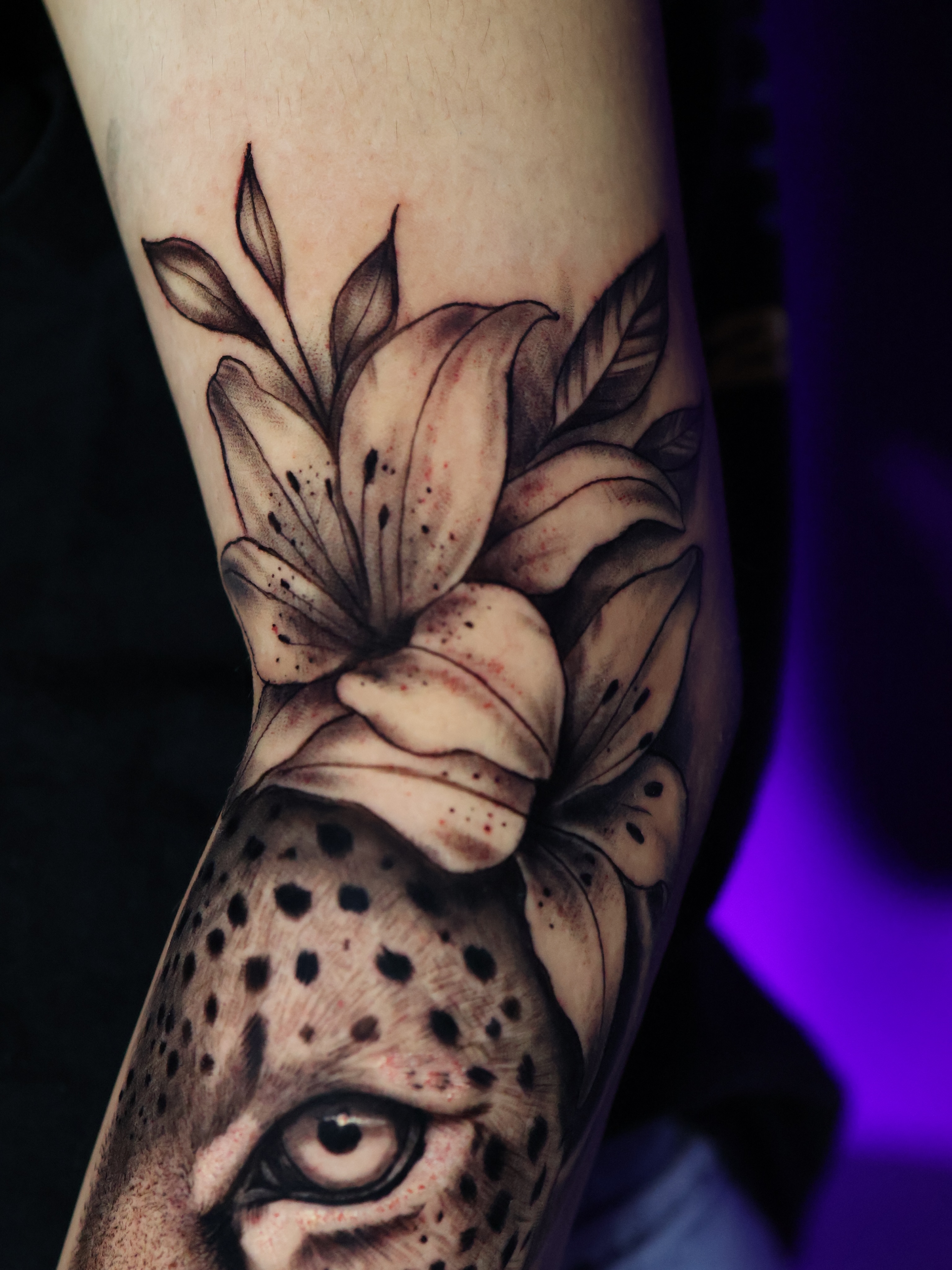 Lily and leopard realism tattoo on the forearm by German Patiño.