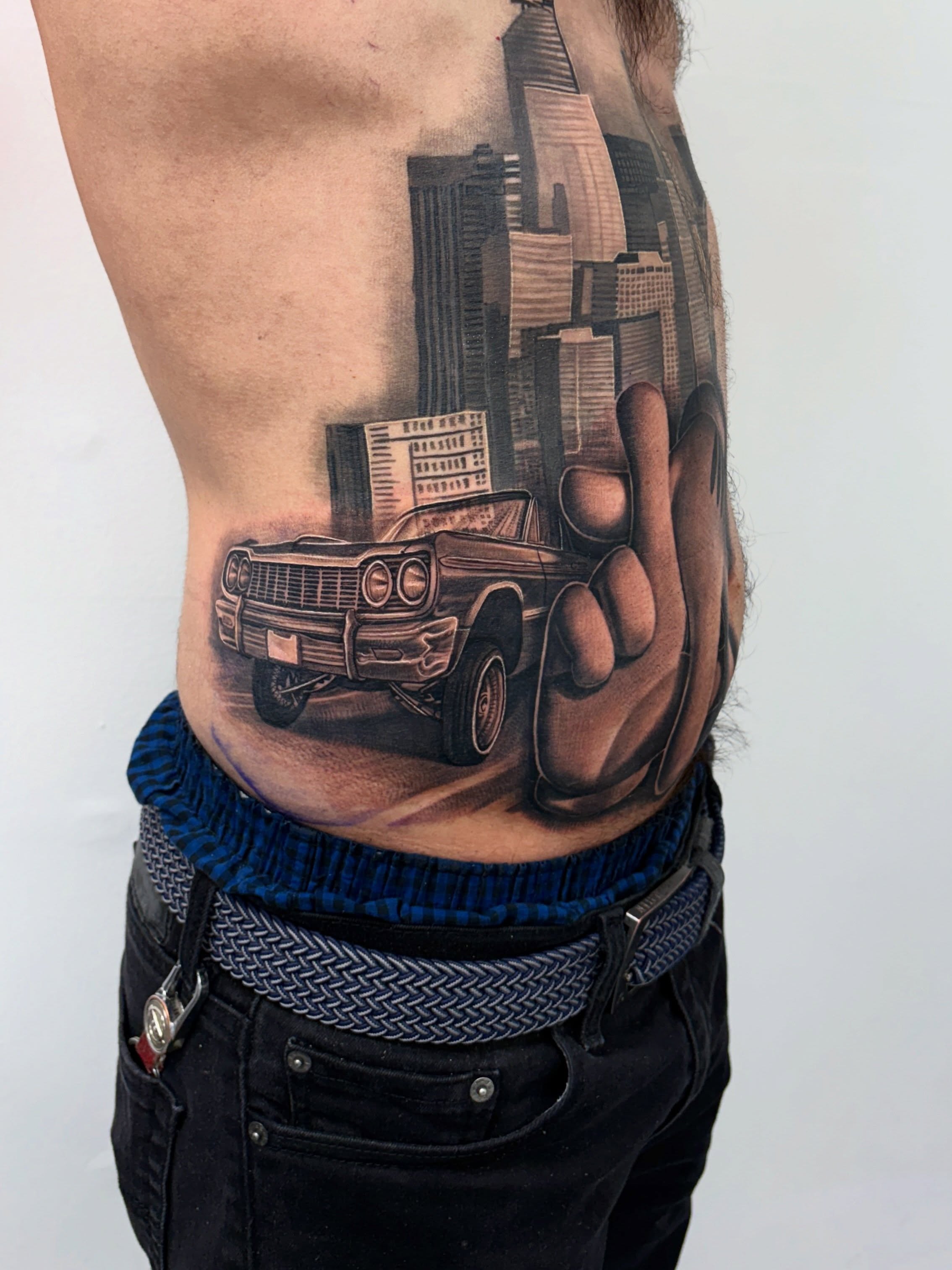 Car and cityscape realism tattoo on the ribs by Anthony Duran