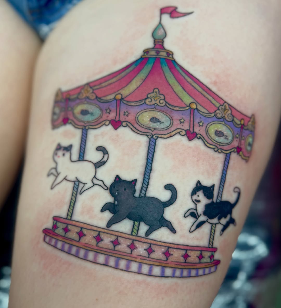 Carousel with cats illustrative tattoo on the thigh by Jada Reynolds