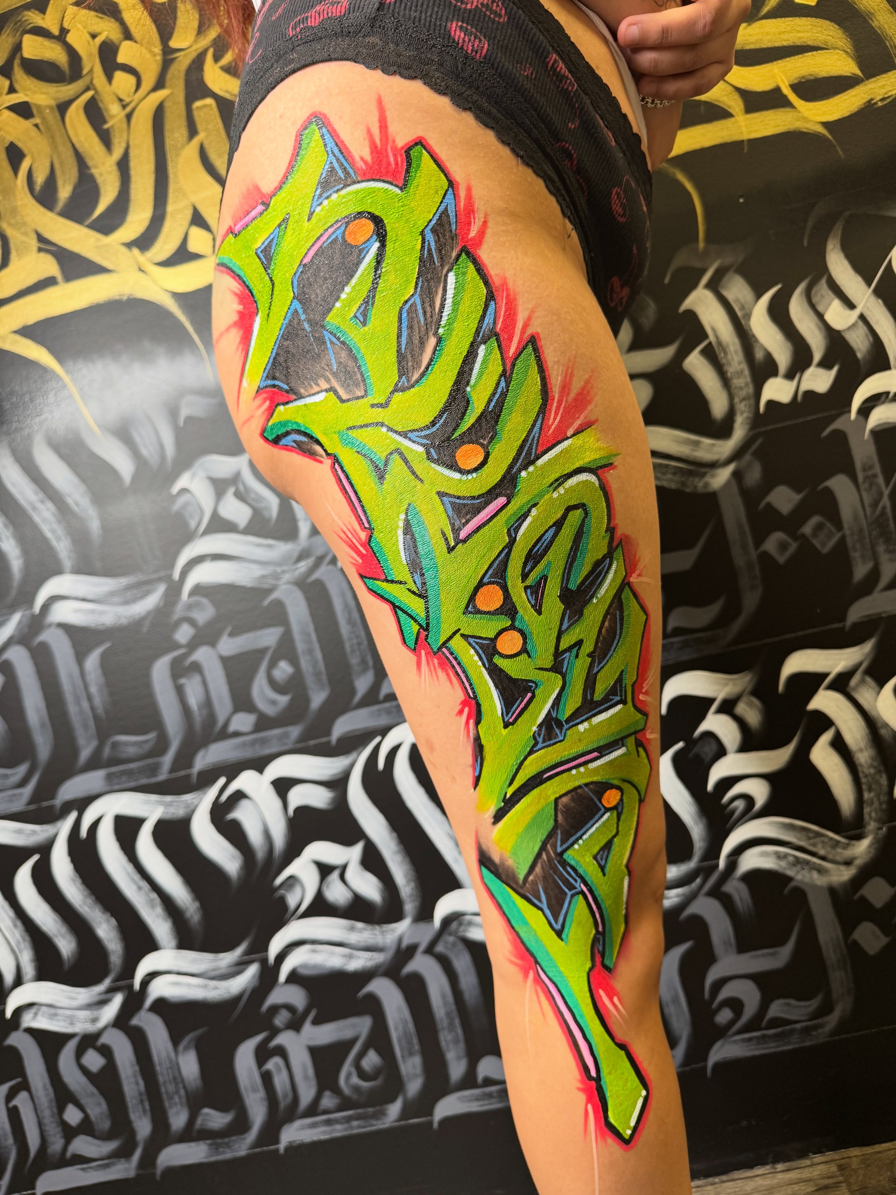 Graffiti-style lettering tattoo on the thigh by North County Sd