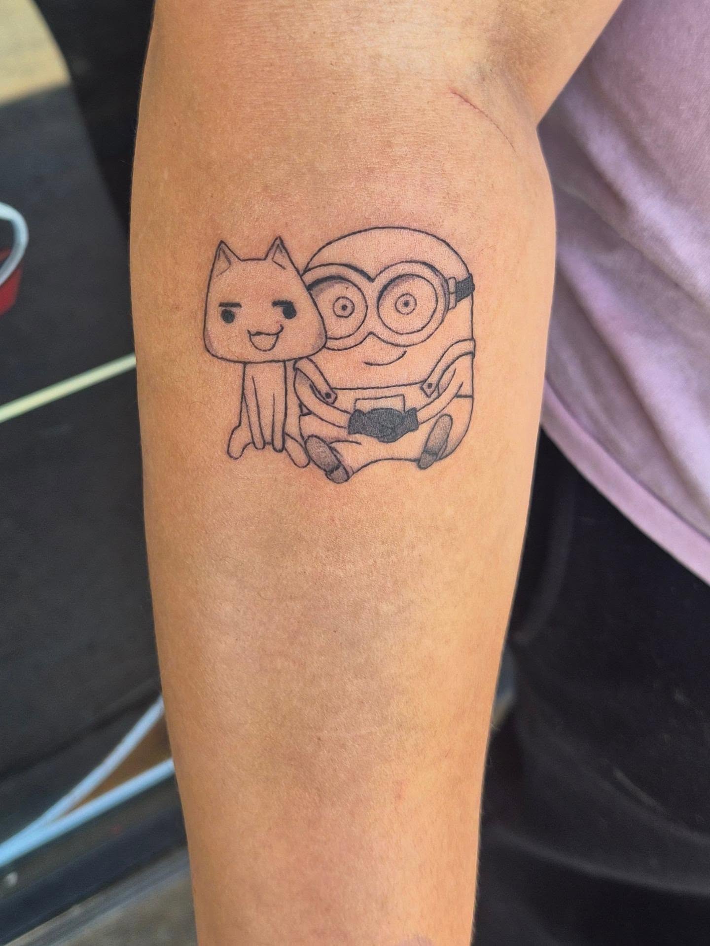 Cat and minion minimalist tattoo on the forearm by Cielle
