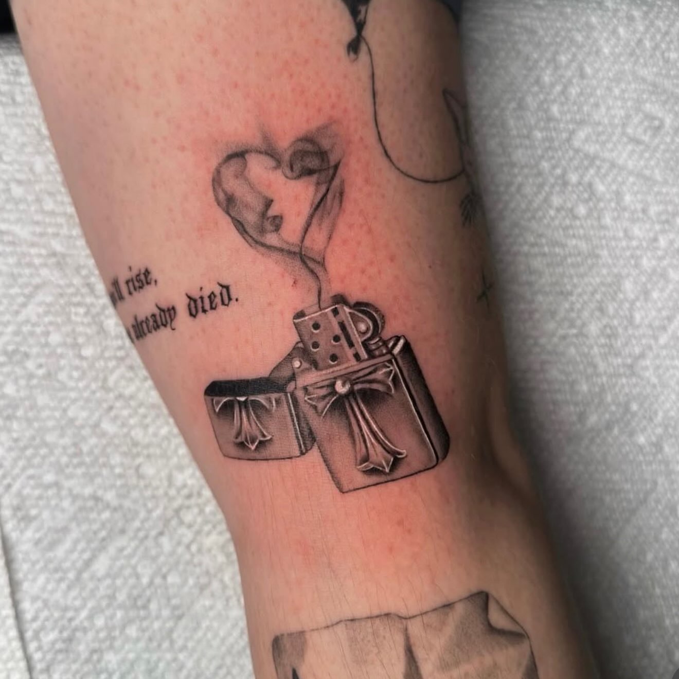 Lighter and heart black and grey tattoo on the forearm by Jas Knight