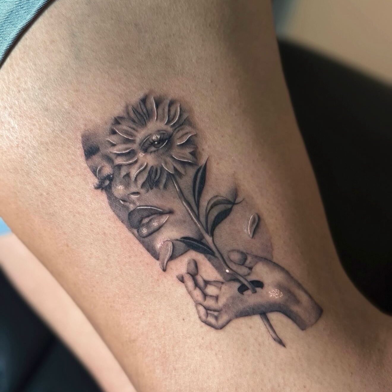 Flower and hand black and grey tattoo on the thigh by Jas Knight