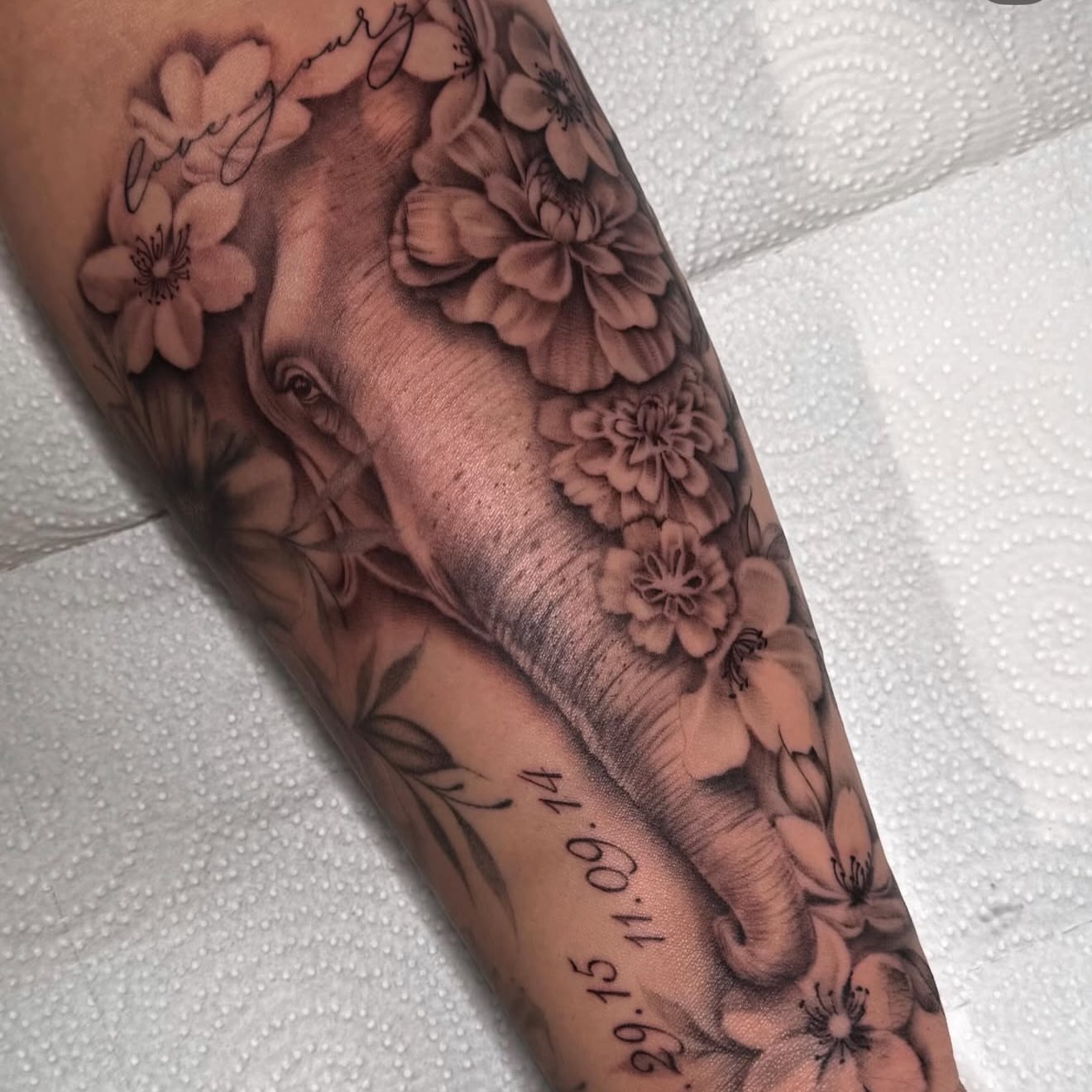 Elephant and flowers realism tattoo on the forearm by Jas Knight
