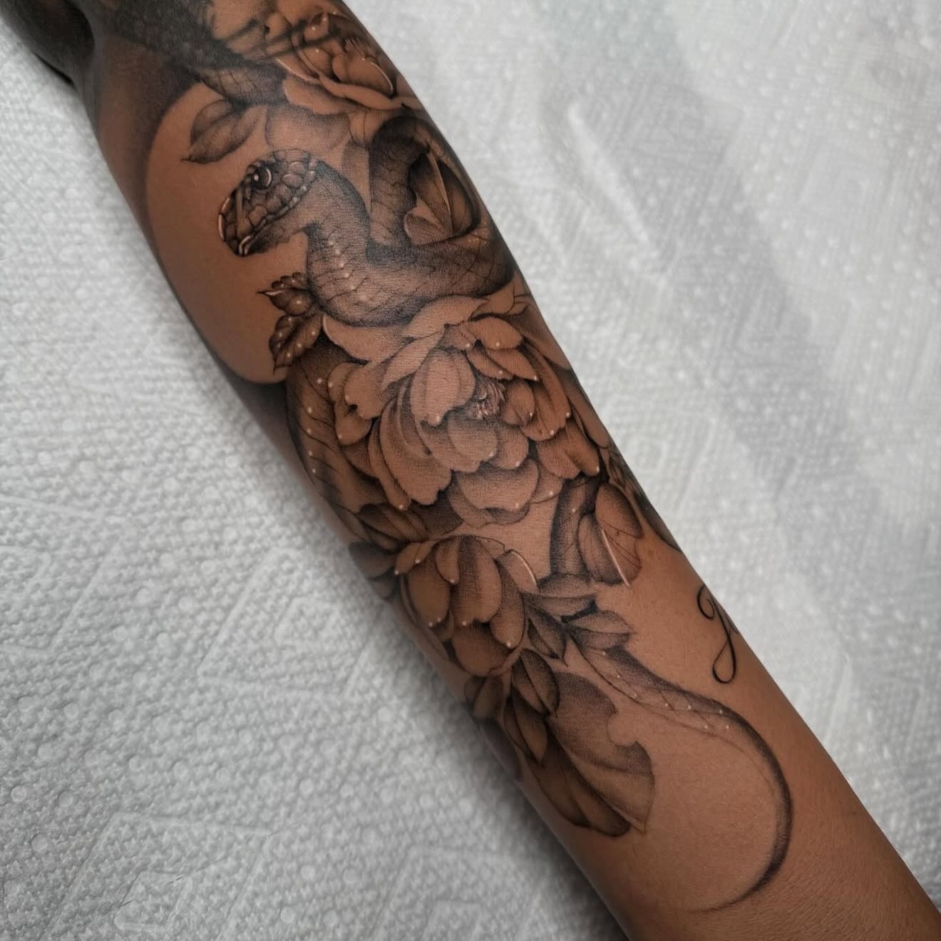 Snake and peony black and grey tattoo on the forearm by Jas Knight