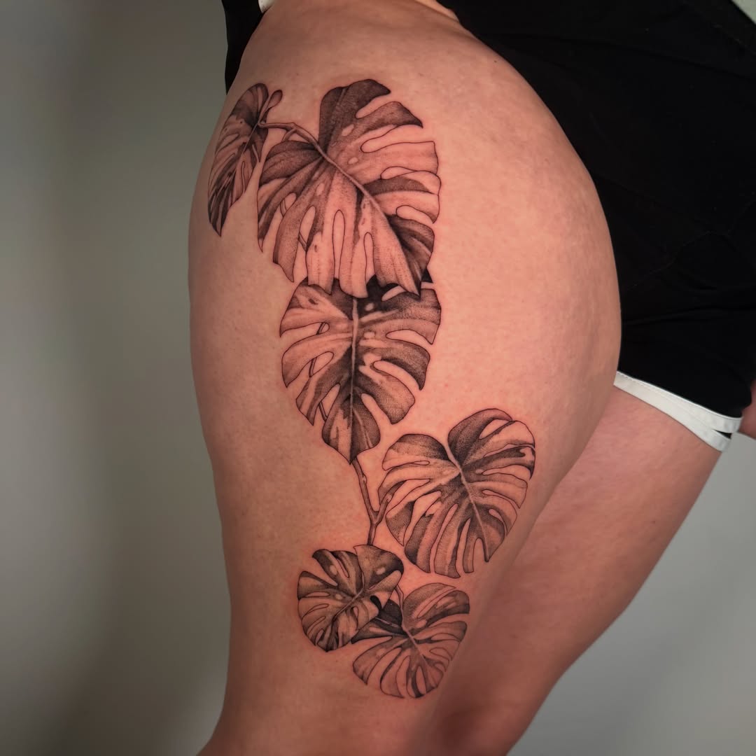 Monstera leaves black and grey tattoo on the thigh by Cyn