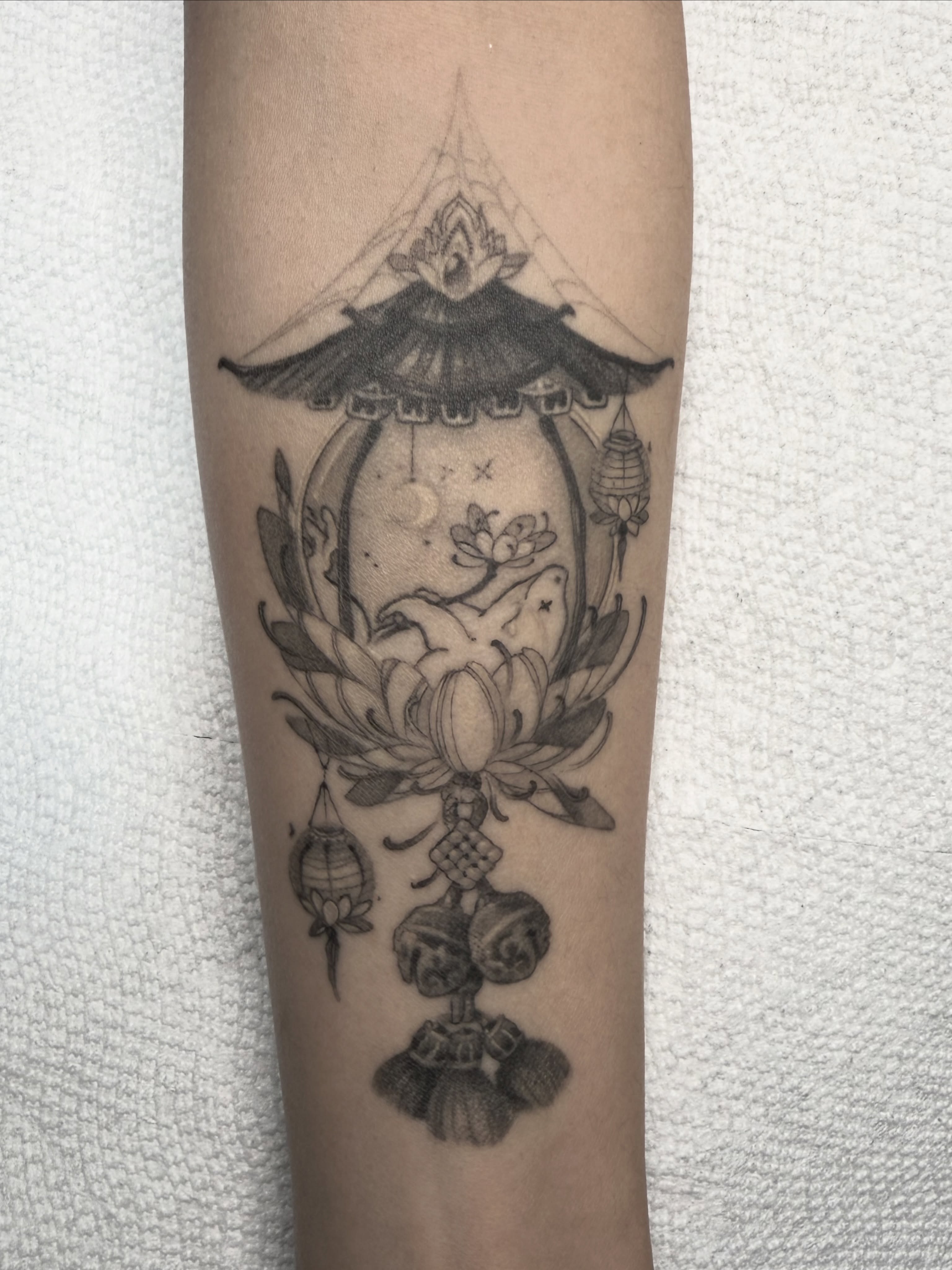 Lotus and pagoda black and grey tattoo on the forearm by Joshua Hung, Alhambra, California