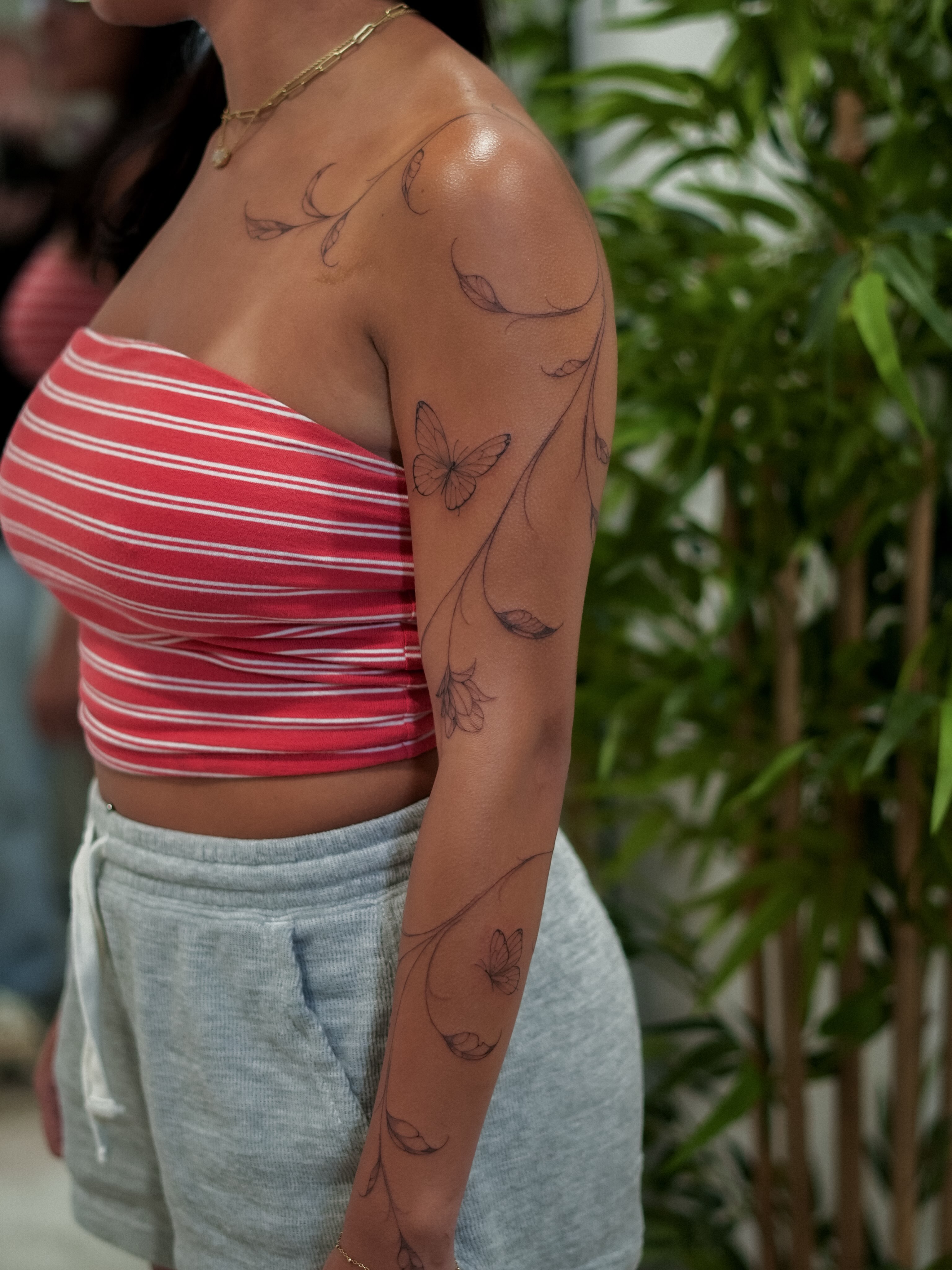 Butterfly and floral vines black and grey tattoo on the upper arm by Adriano Bassalo