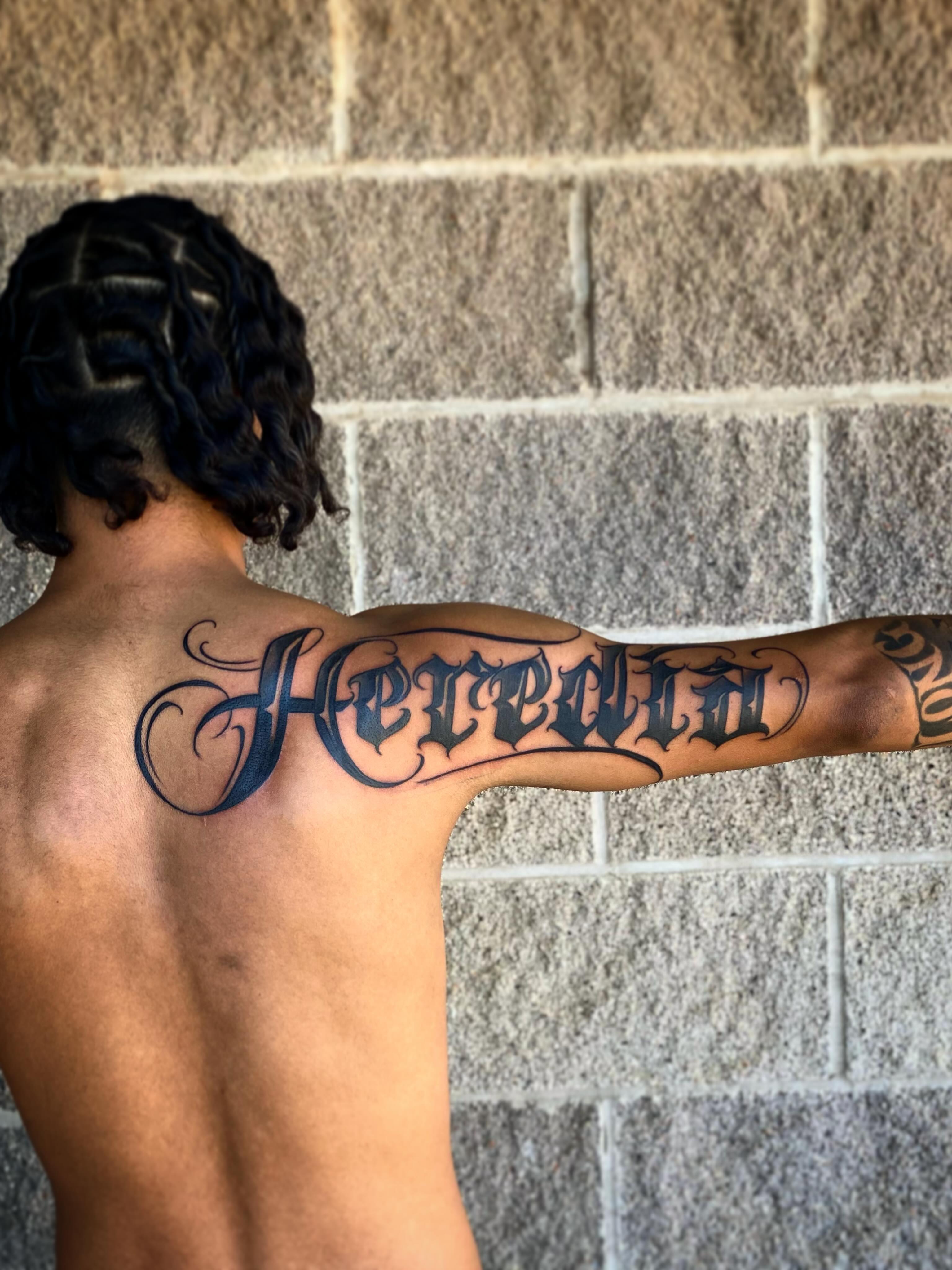 Heredia lettering script tattoo on the back by Lex Miranda