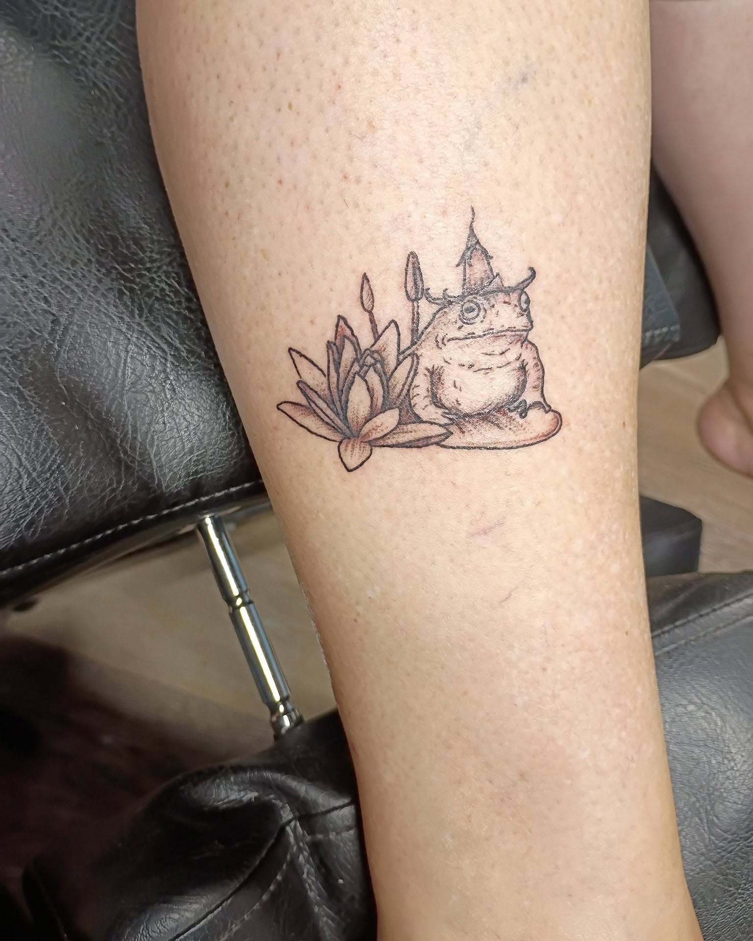 Frog with hat black and grey tattoo on the forearm by Tiffany