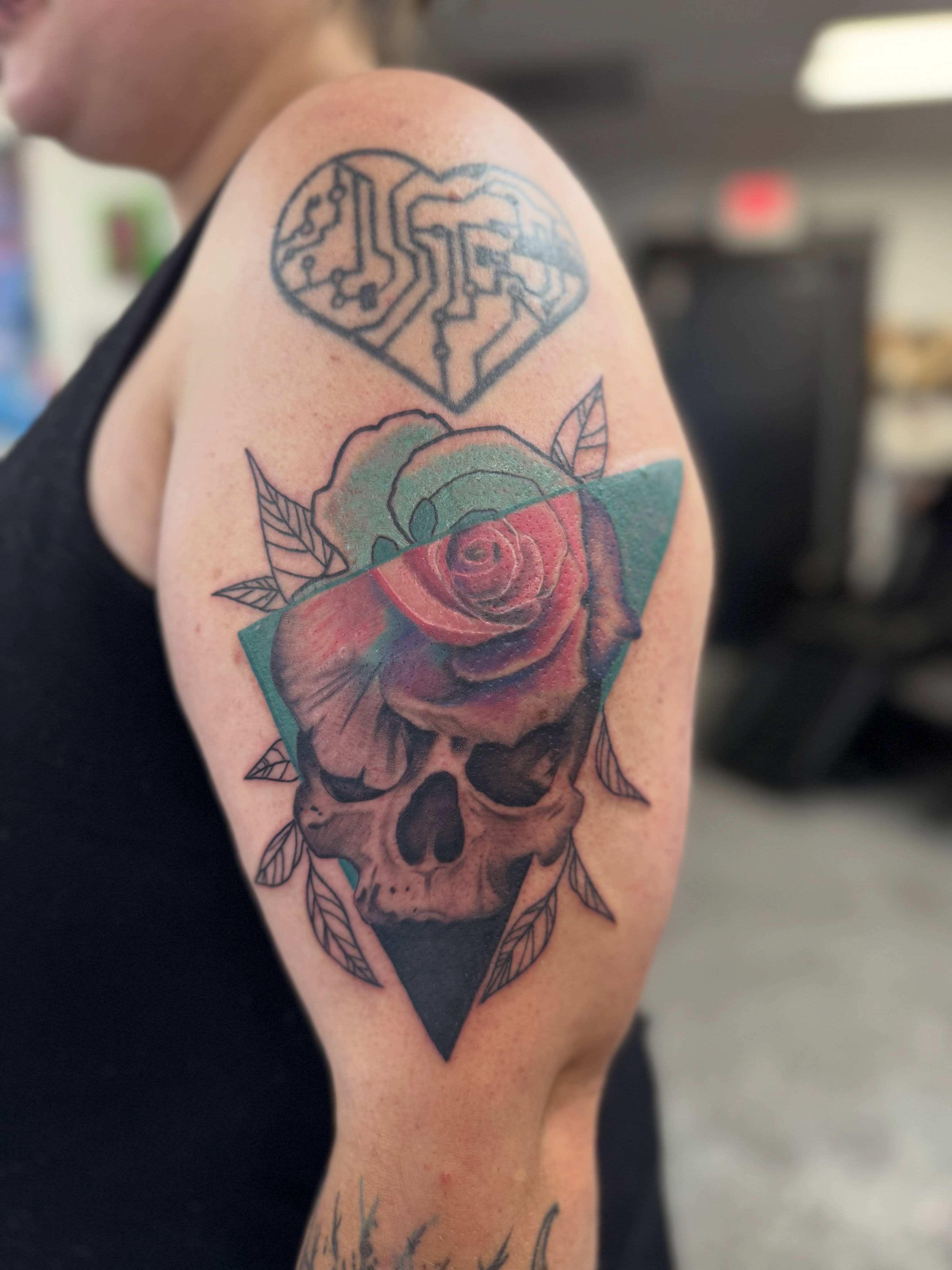 Skull and rose realism tattoo on the upper arm by “tatsbysabby”