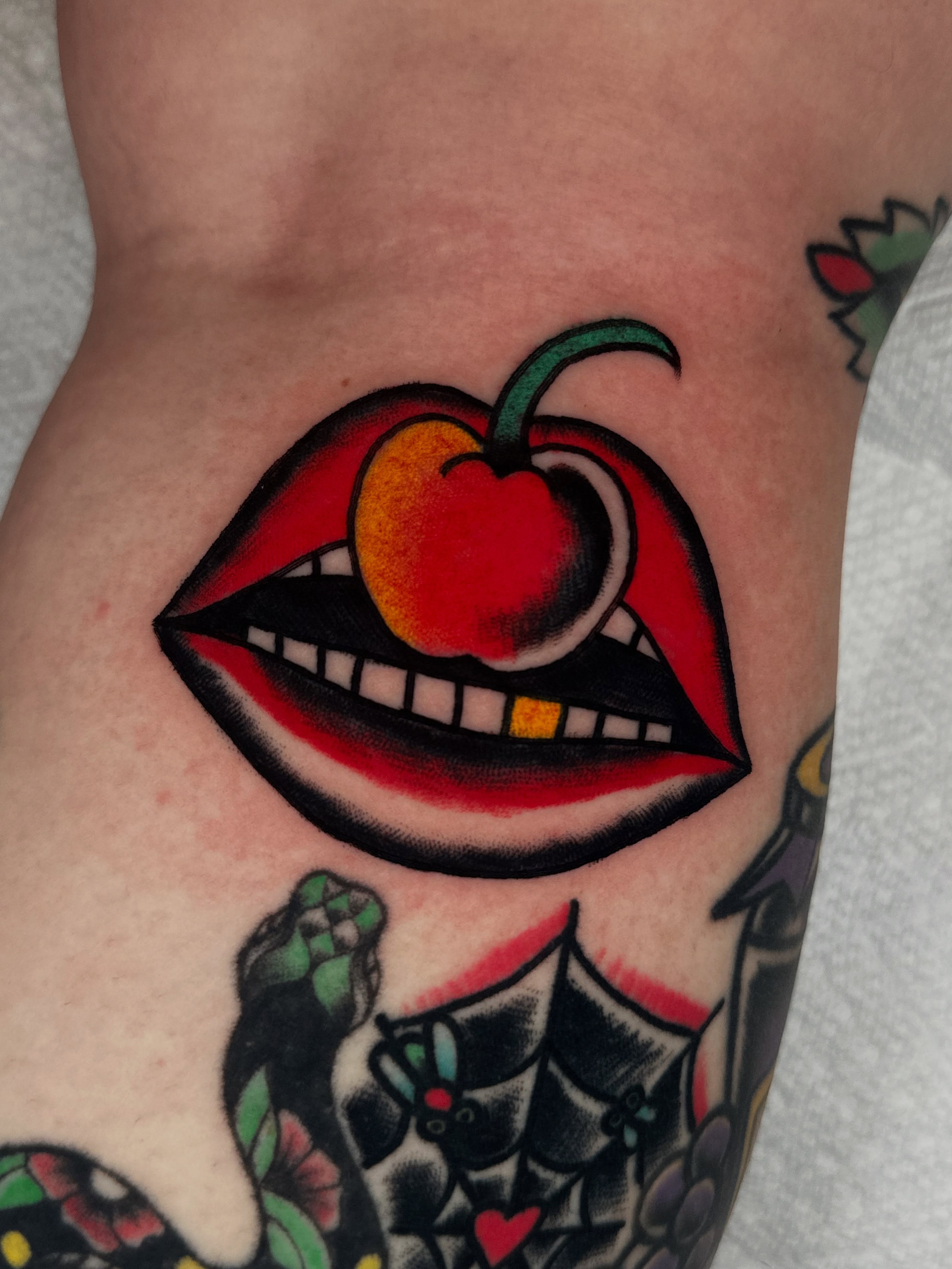 Lips and cherry American traditional tattoo on the forearm by Spencer Crawford, Speedway, Indiana
