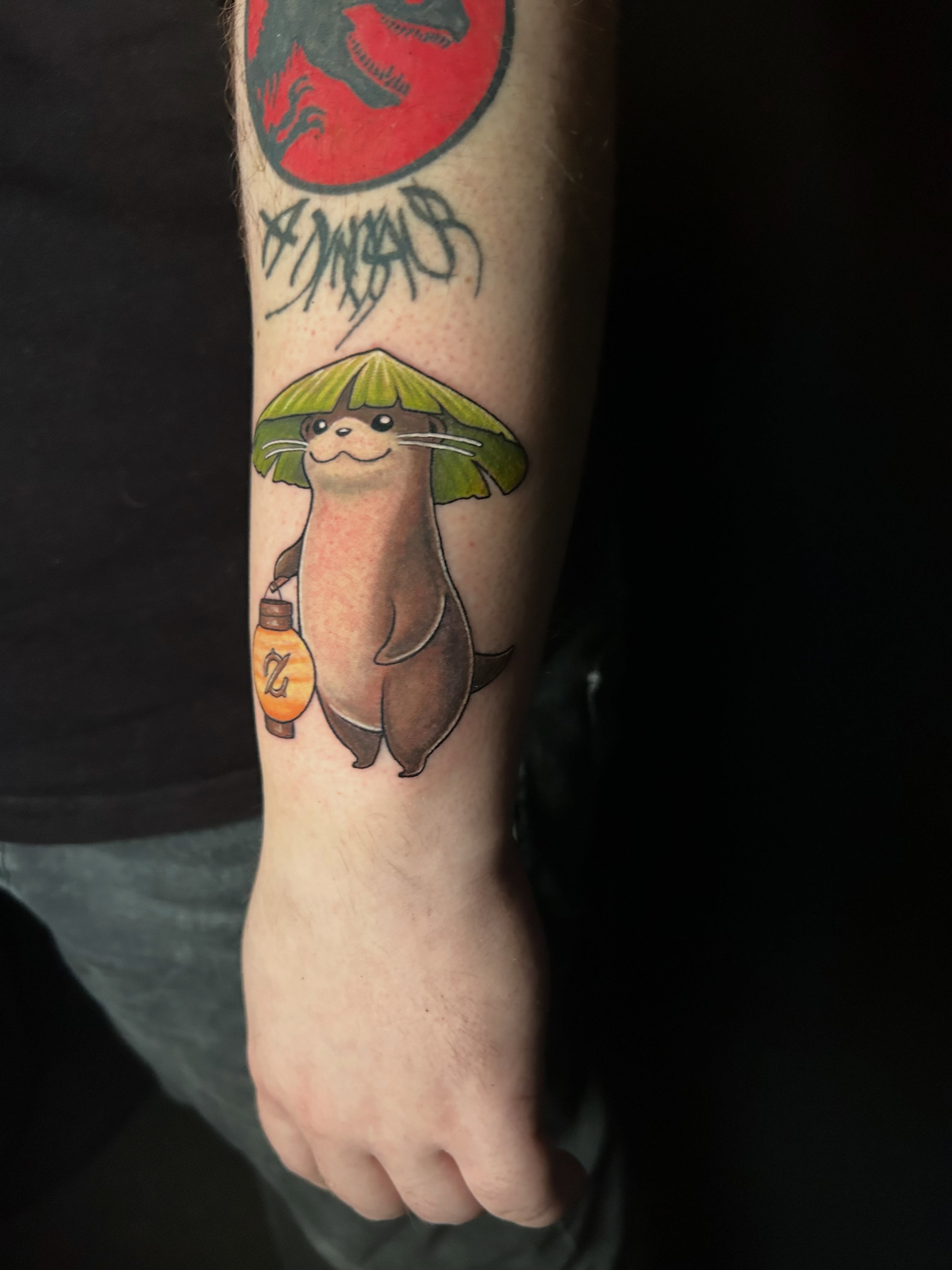 Otter holding umbrella realism tattoo on the forearm by Michigan Tattoo Artist - Emily Borneman
