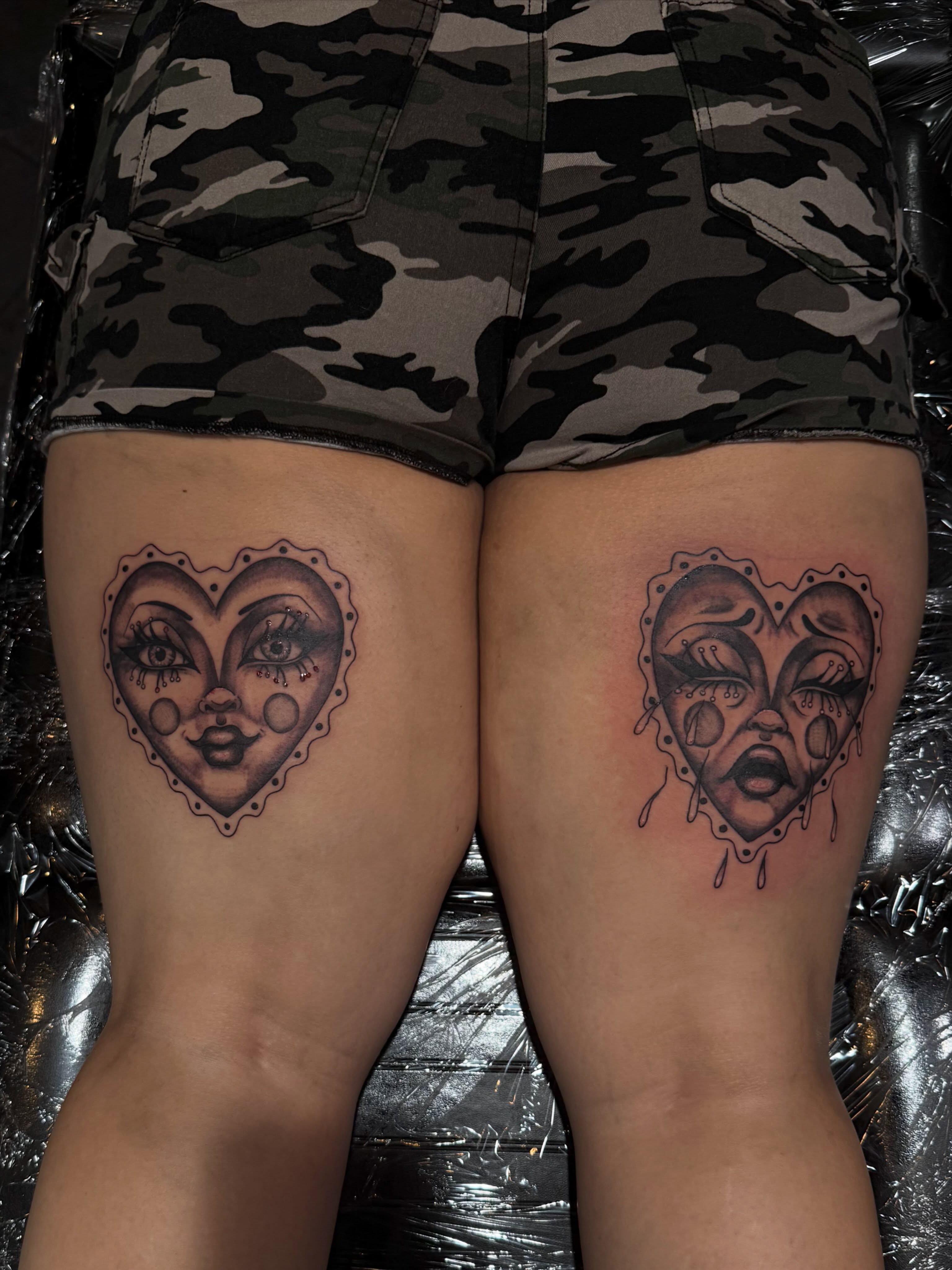 Heart faces black and grey tattoo on the thigh by Courtney