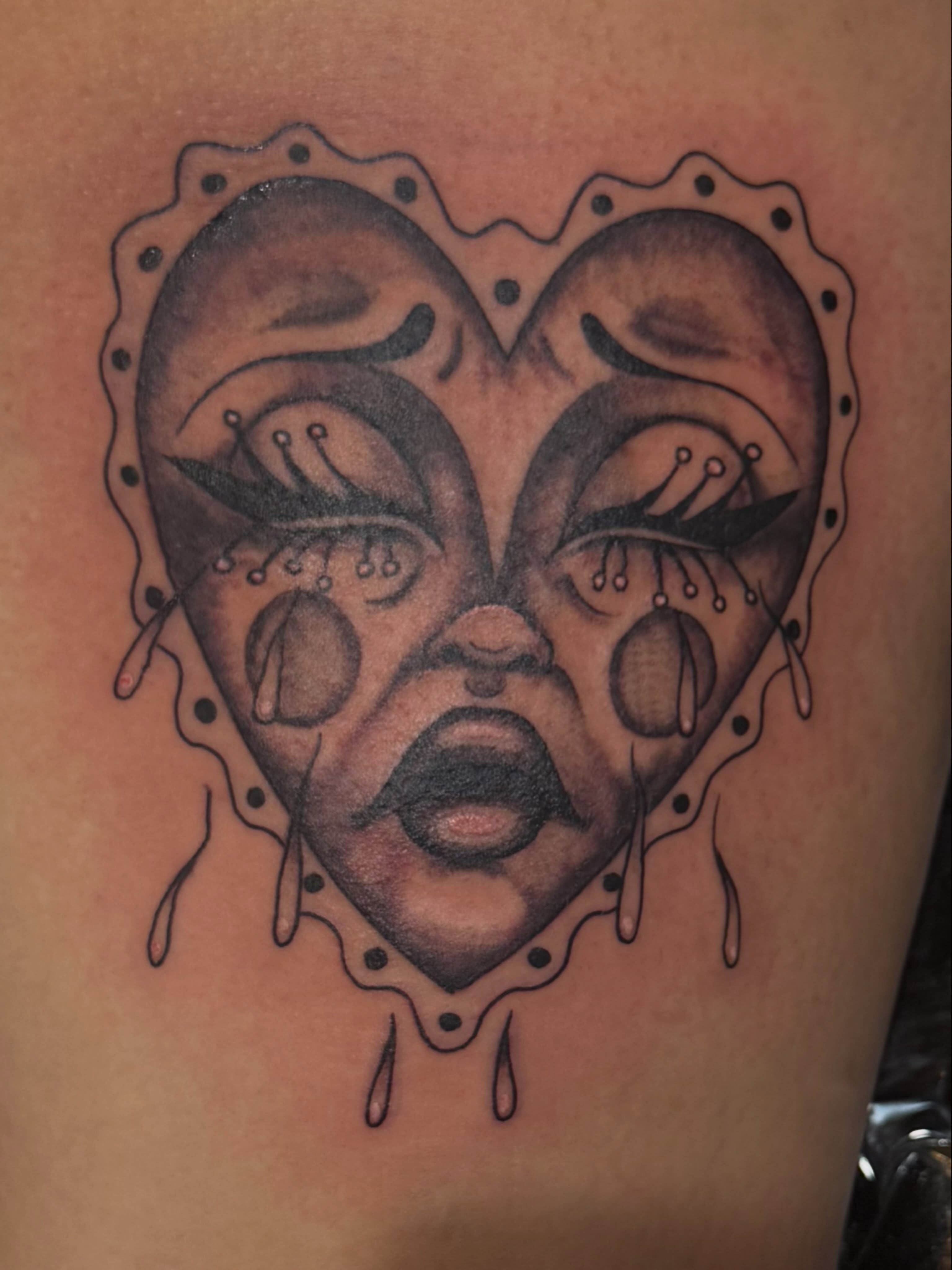 Heart with face black and grey tattoo on the thigh by Courtney