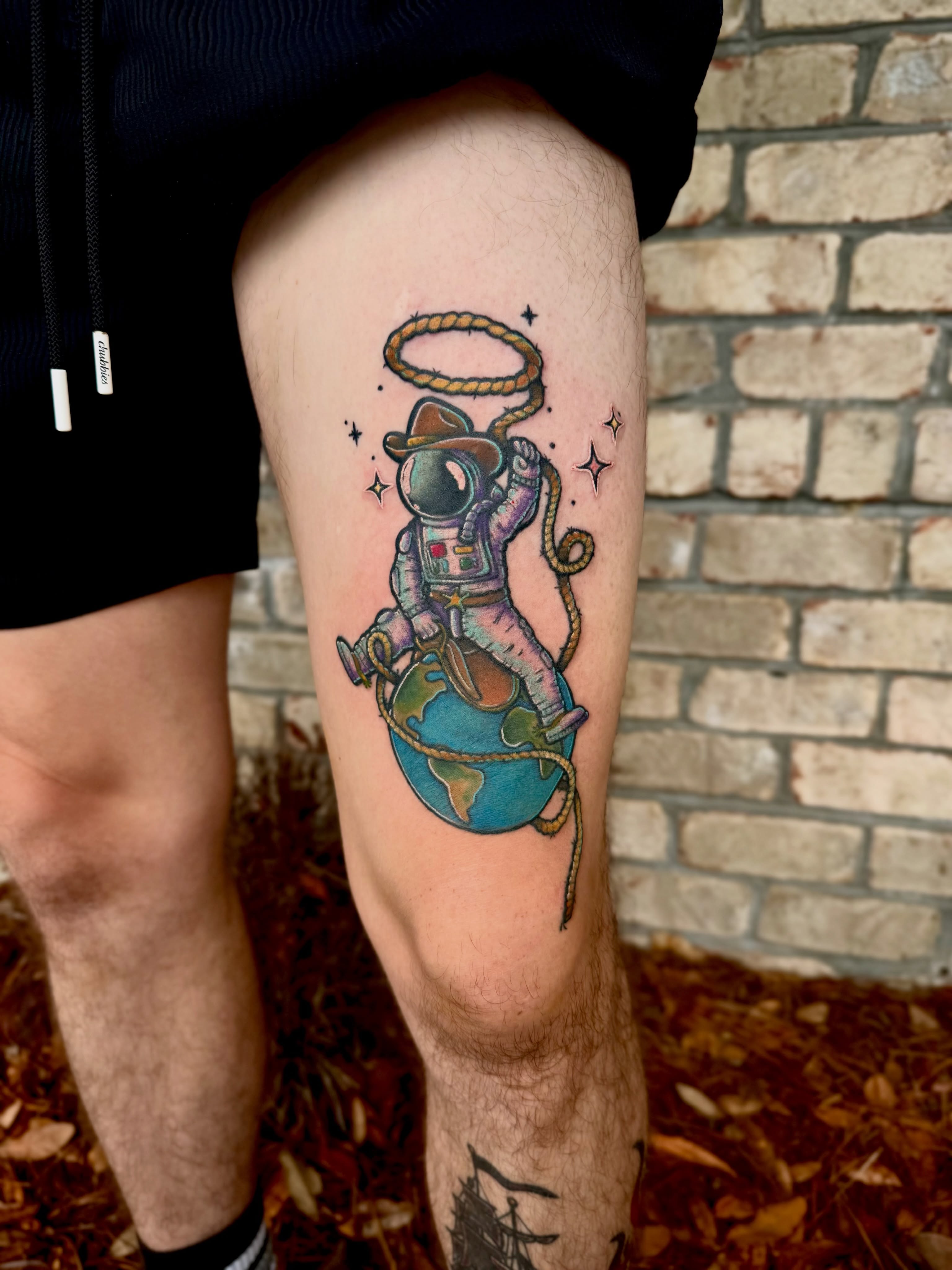 Astronaut on Earth illustrative tattoo on the thigh by Brooke Sombati