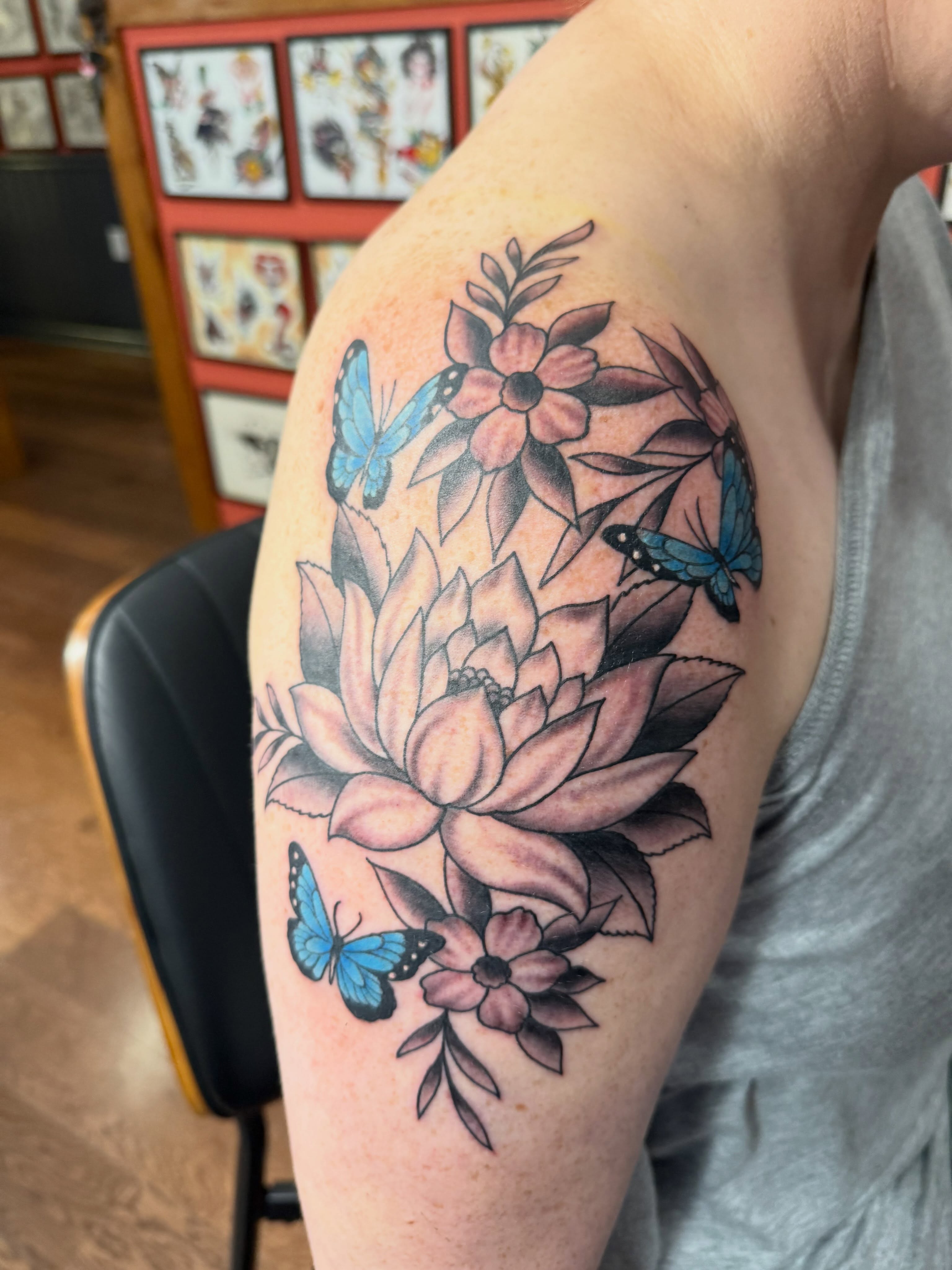 Lotus flower and butterflies watercolor tattoo on the upper arm by Cody Dalton