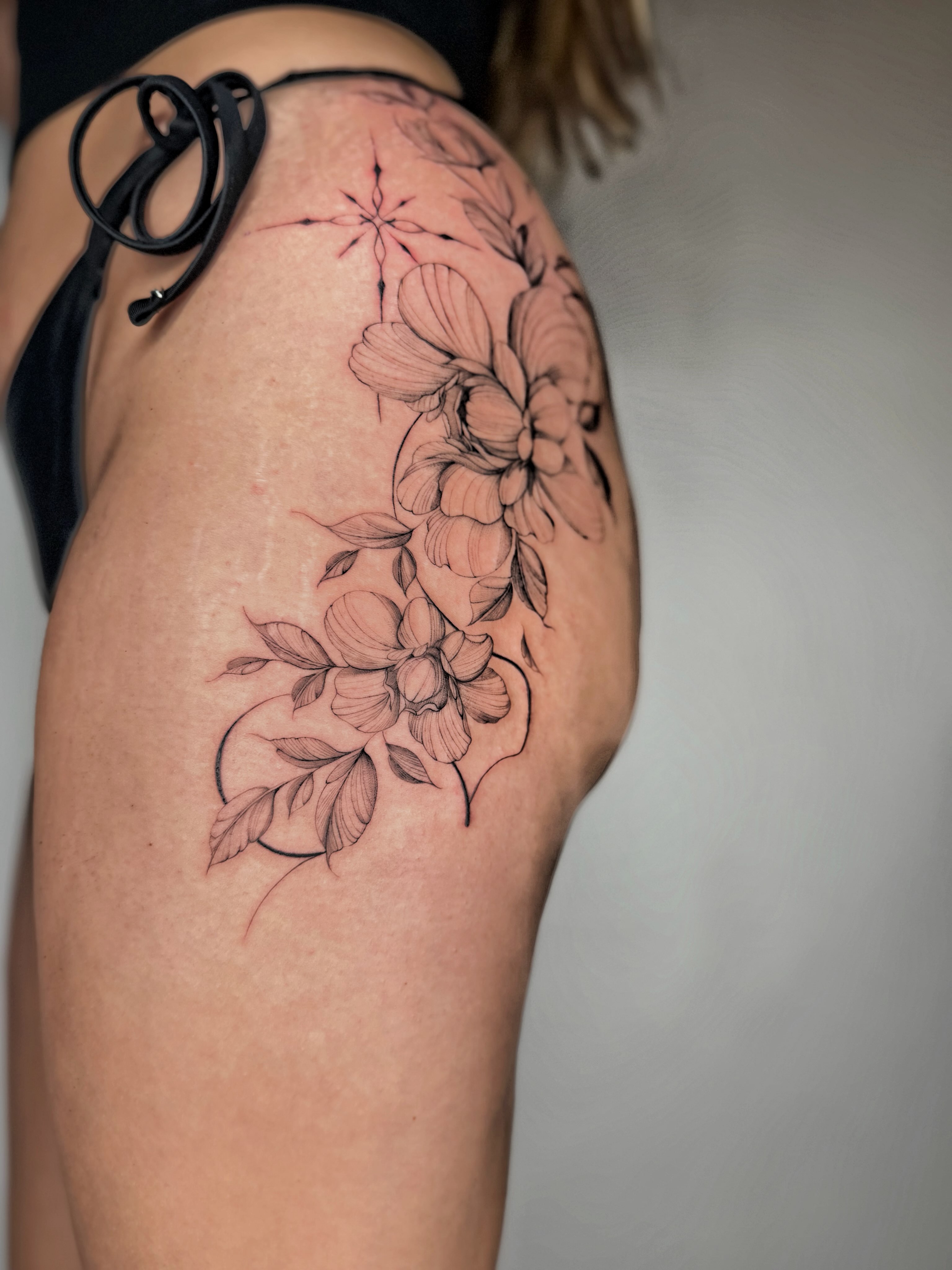 Floral arrangement black and grey tattoo on the thigh by ꜰɪɴᴇ ʟɪɴᴇ ᴛᴀᴛᴛᴏᴏꜱ