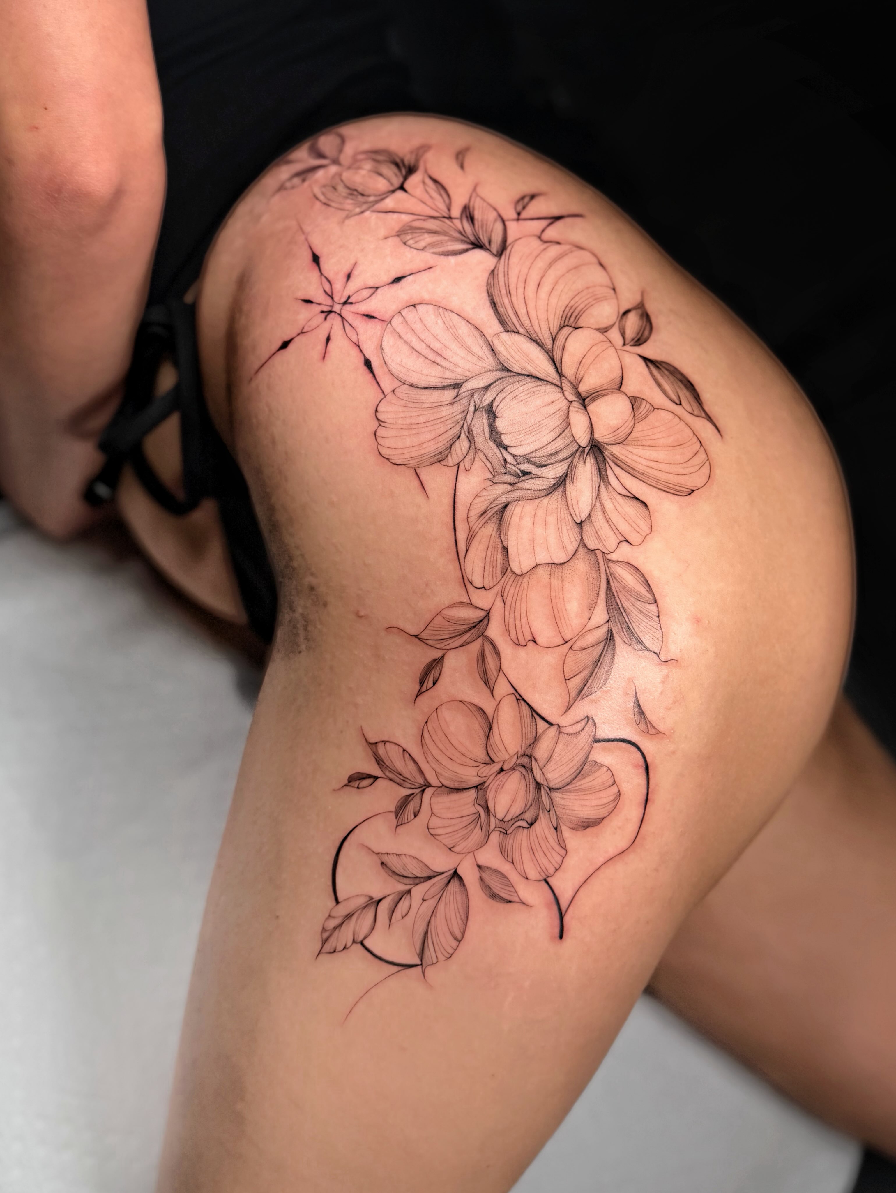 Floral arrangement black and grey tattoo on the thigh by ꜰɪɴᴇ ʟɪɴᴇ ᴛᴀᴛᴛᴏᴏꜱ