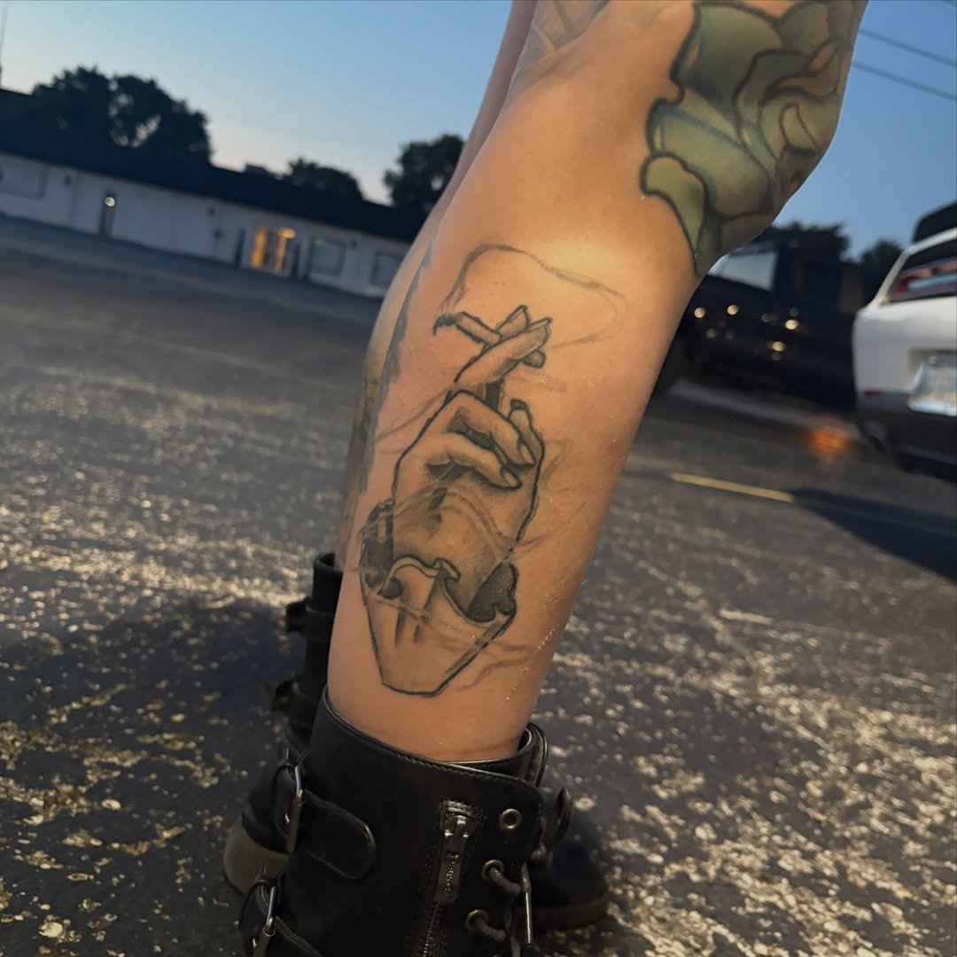 Hand holding cigarette black and grey tattoo on the forearm by Joshua Scott