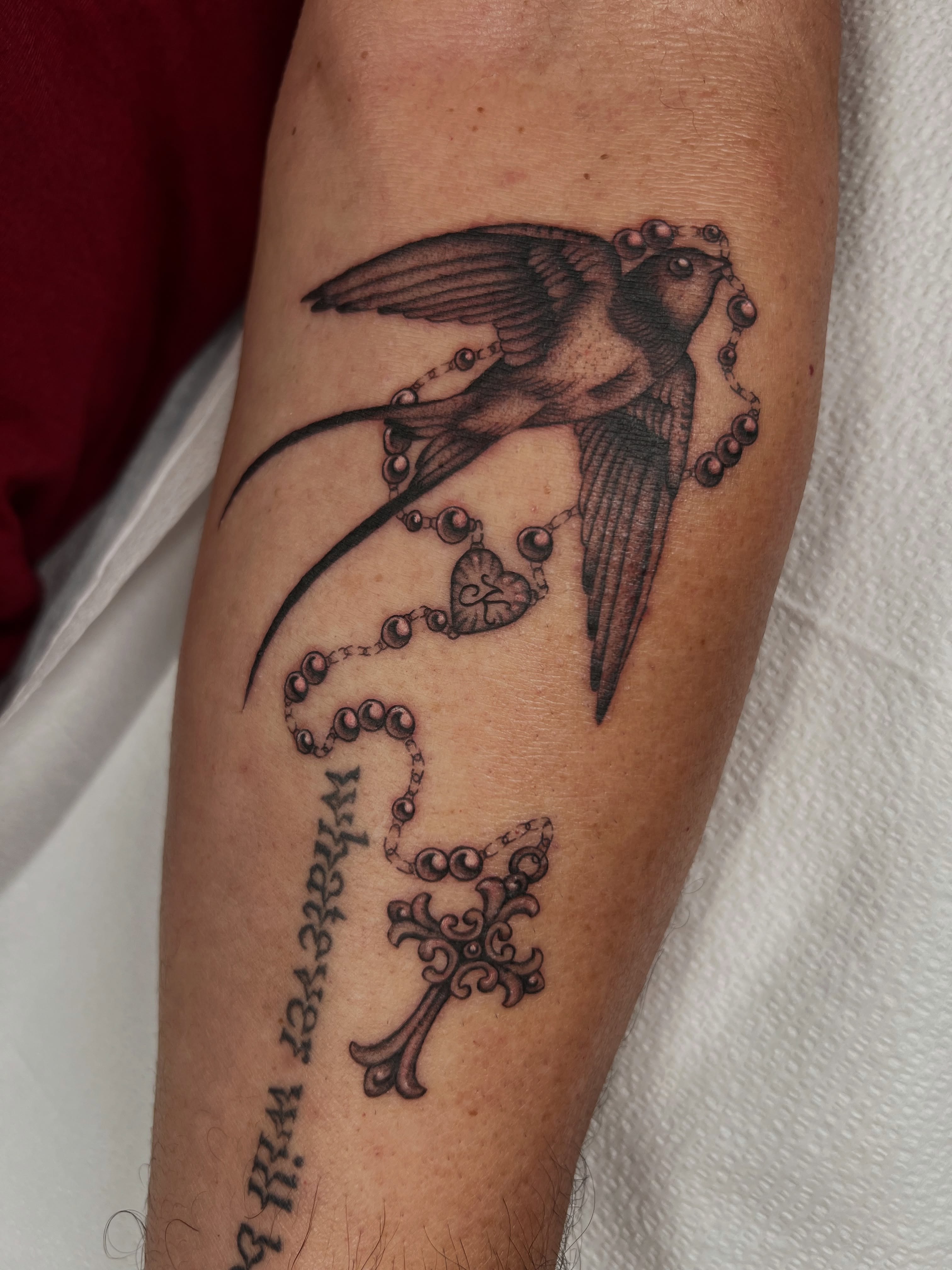 Swallow and rosary black and grey tattoo on the forearm by Cassidy Maples