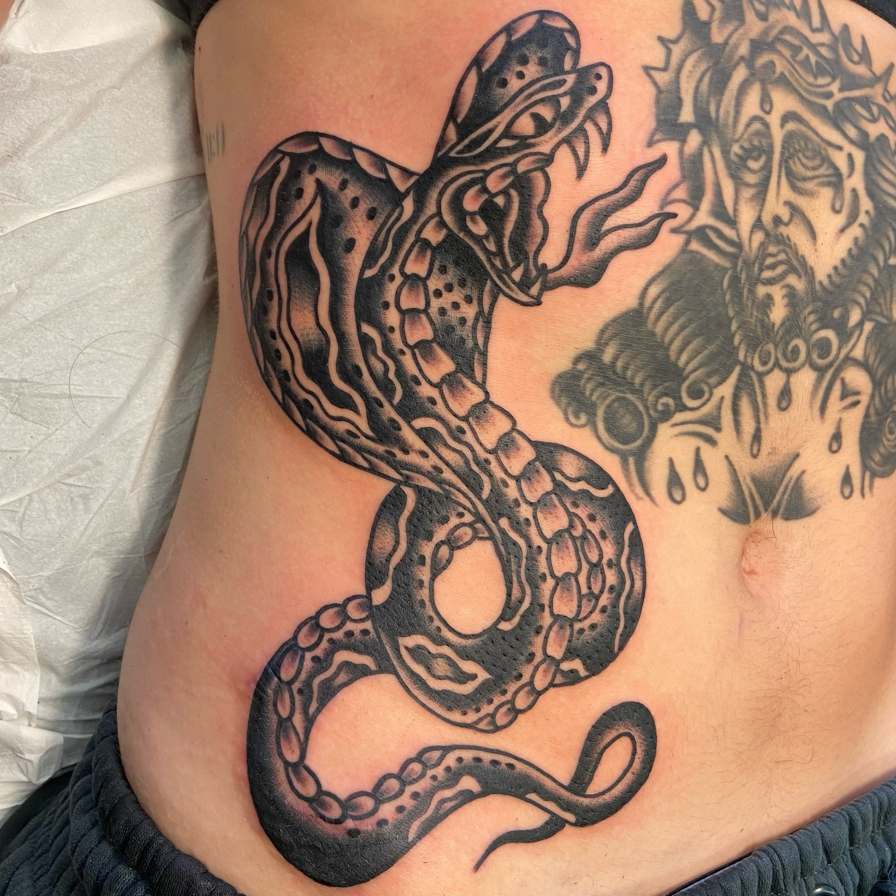 Snake black and grey tattoo on the ribs by Anthony Jaeger, Seattle, Washington