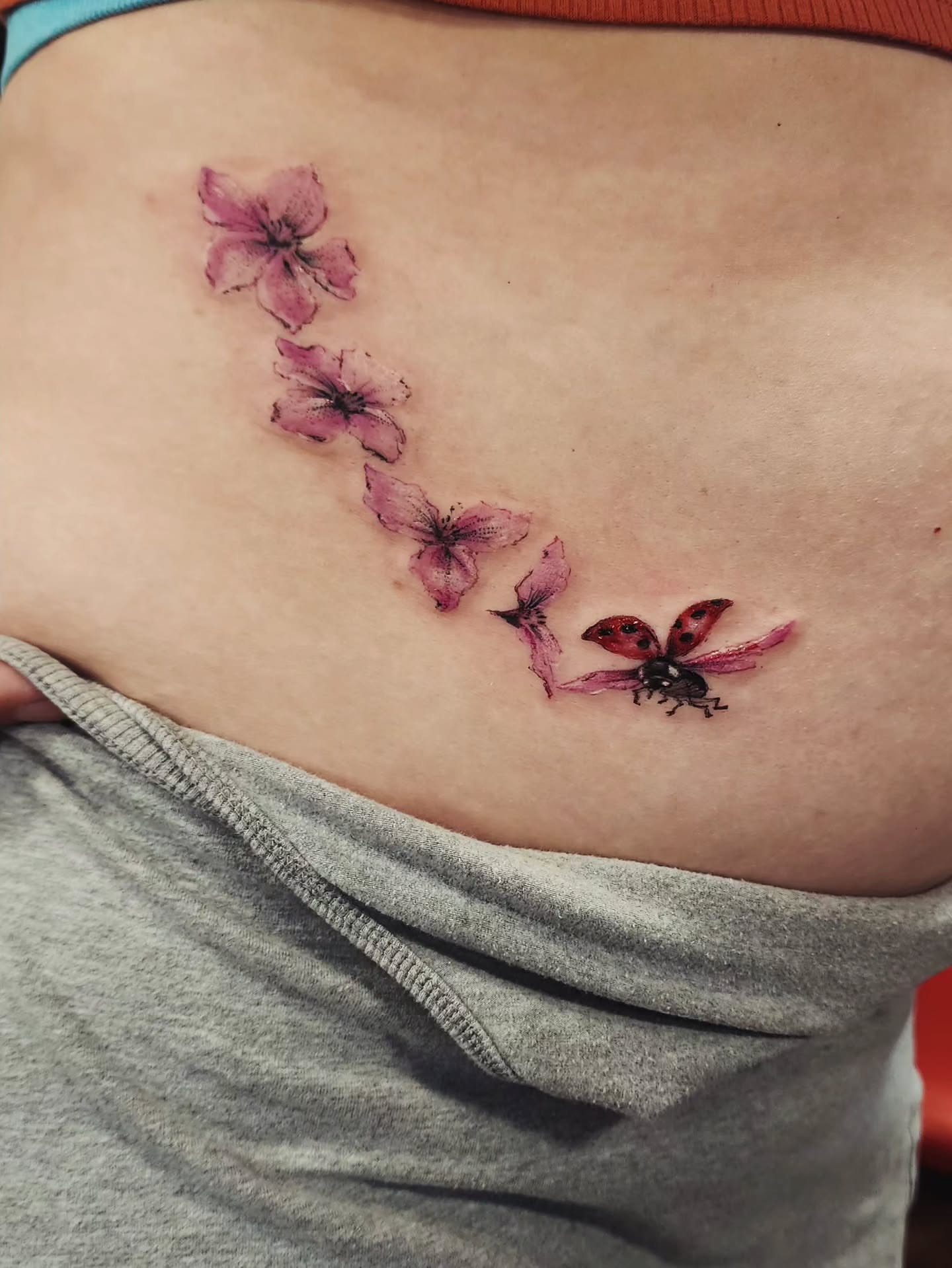 Cherry blossoms and ladybug realism tattoo on the ribs by Dr. Valerio Vegas Tattoo