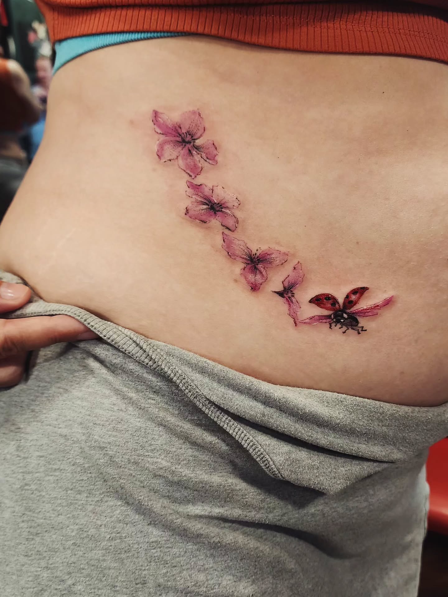 Flowers and ladybug watercolor tattoo on the ribs by Dr. Valerio Vegas Tattoo