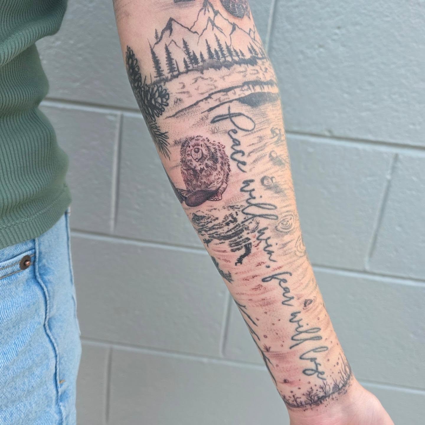 Mountain landscape realism tattoo on the forearm by Maggie