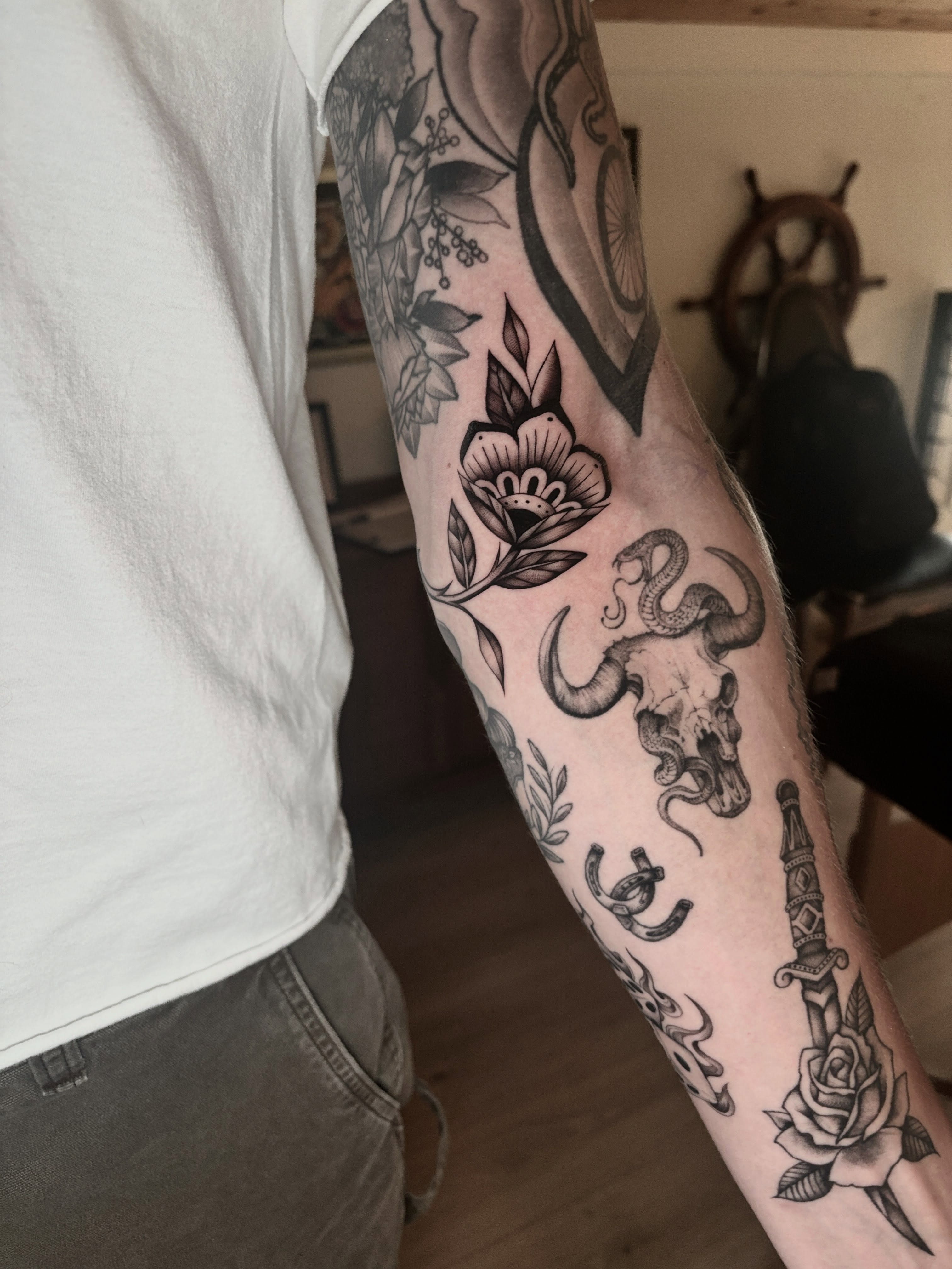 Bull skull and snake black and grey tattoo on the forearm by Emma Cotter