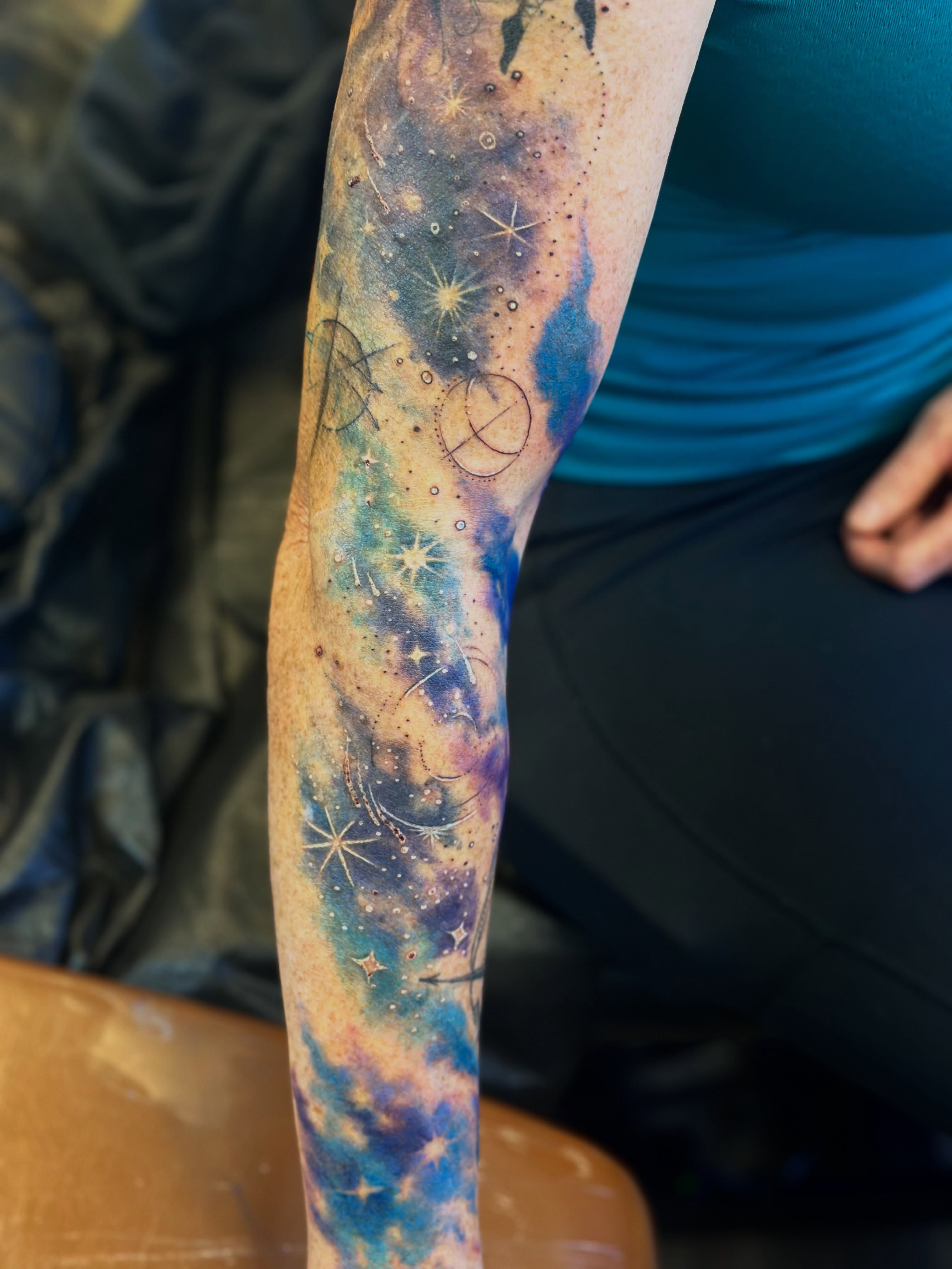 Galaxy watercolor tattoo on the forearm by Teddi Bird