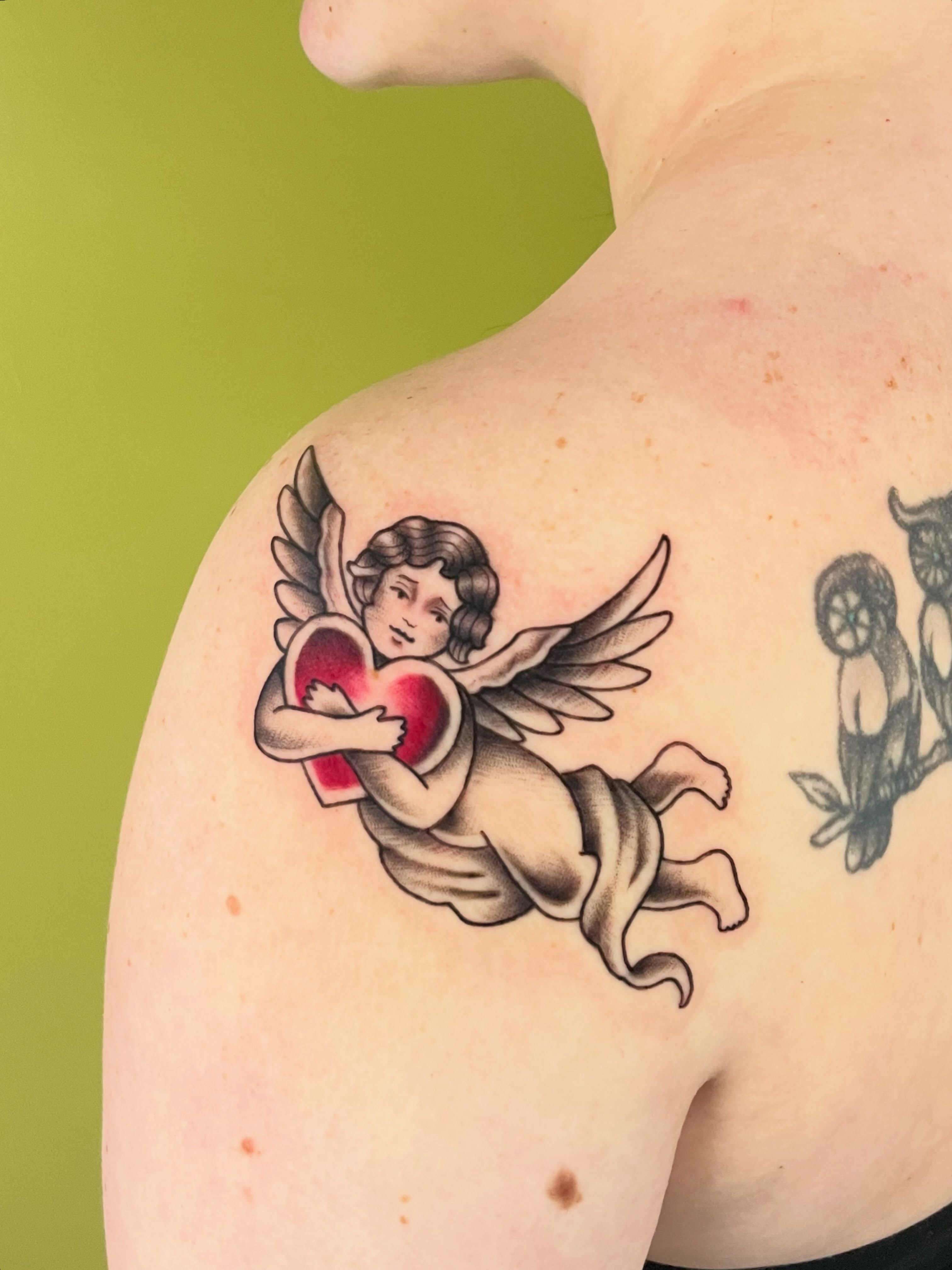 Cherub holding heart American traditional tattoo on the shoulder by ✨Erin Haines✨