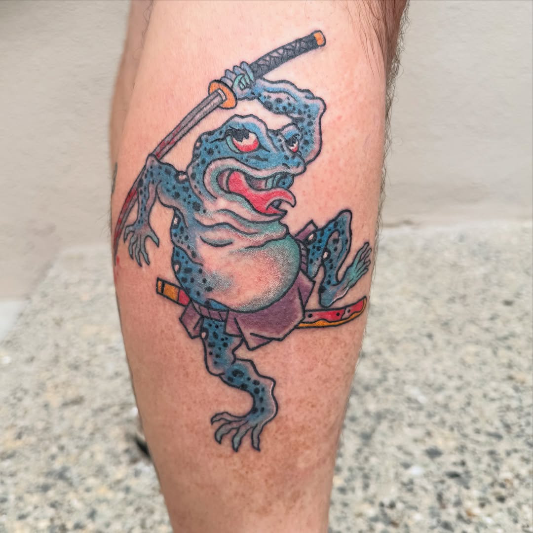 Frog with sword new school tattoo on the leg by Aidan Monahan Tattoo