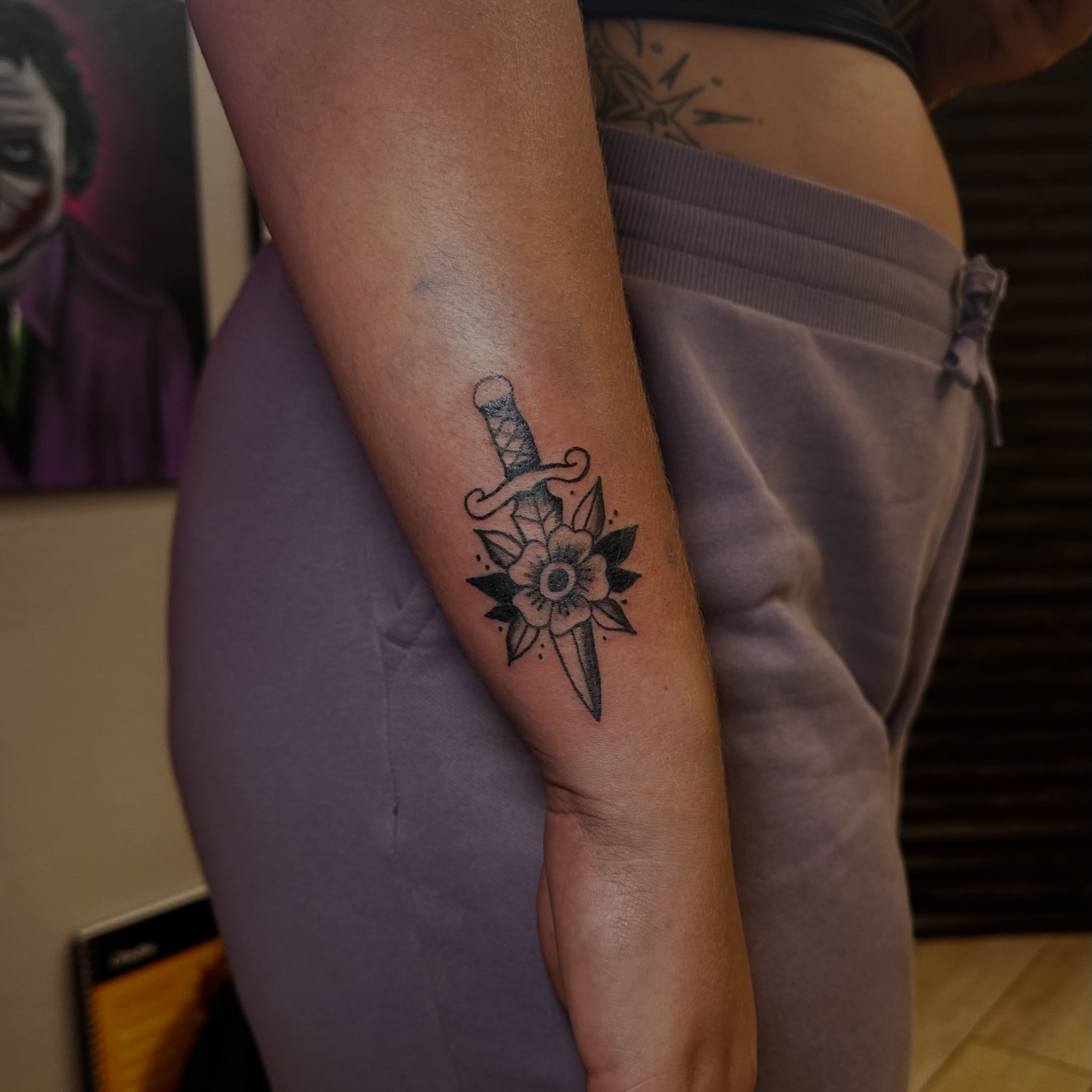 Sword and flower black and grey tattoo on the forearm by Marly Quinn