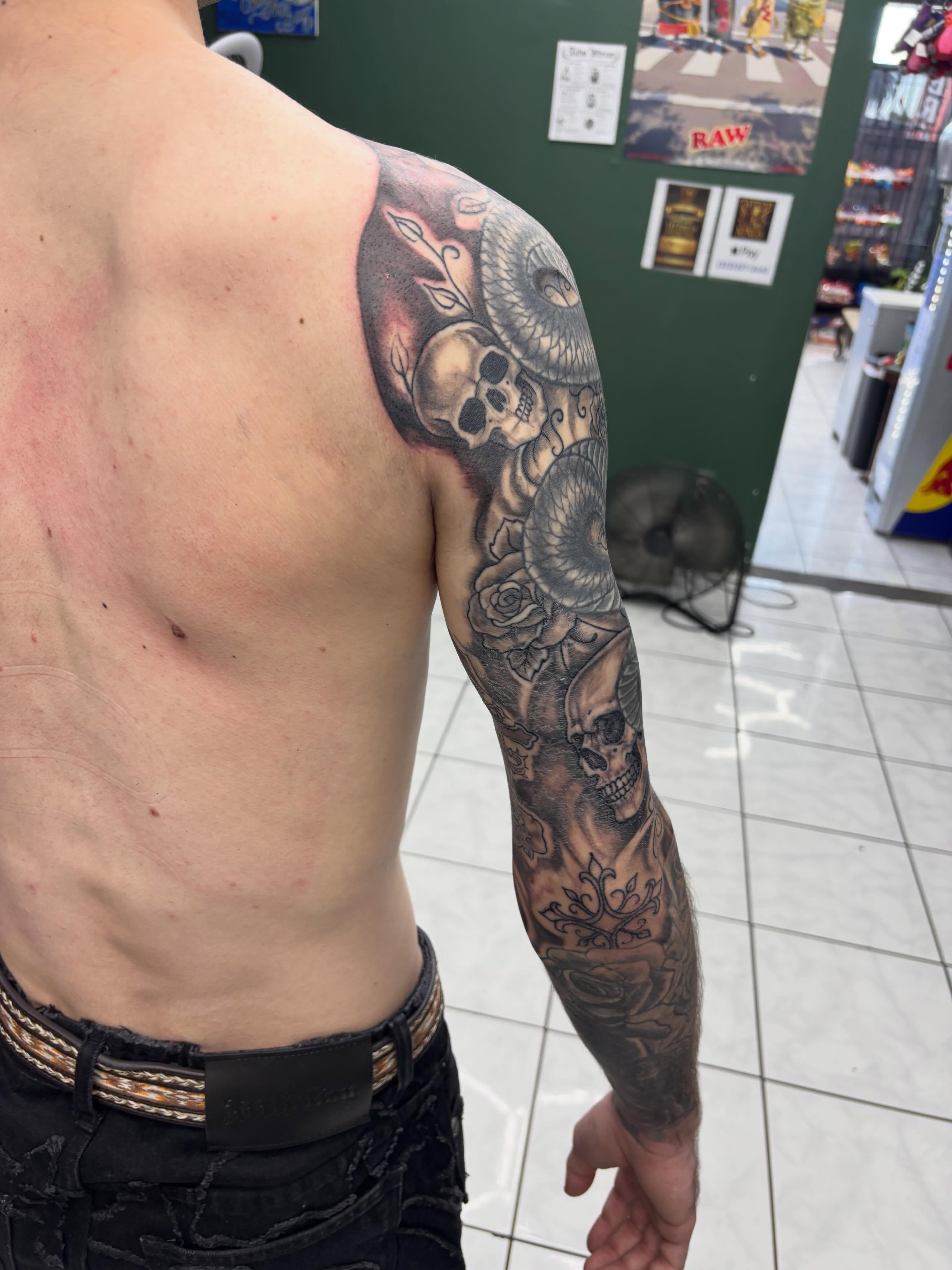 Skulls and roses realism tattoo on the upper arm by Shadows Tattoos